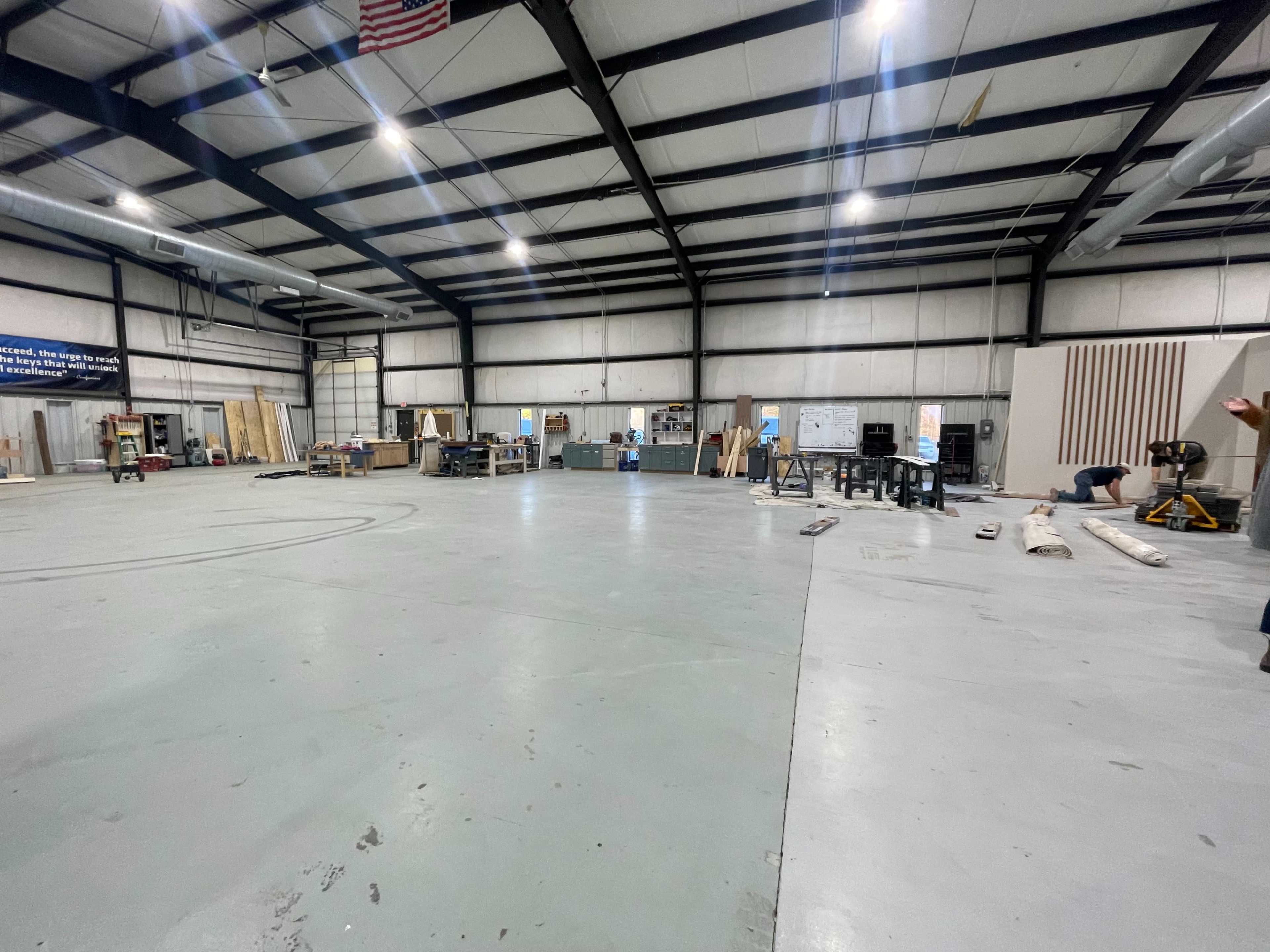 The image depicts a spacious industrial workshop with various tools and equipment arranged throughout the area.