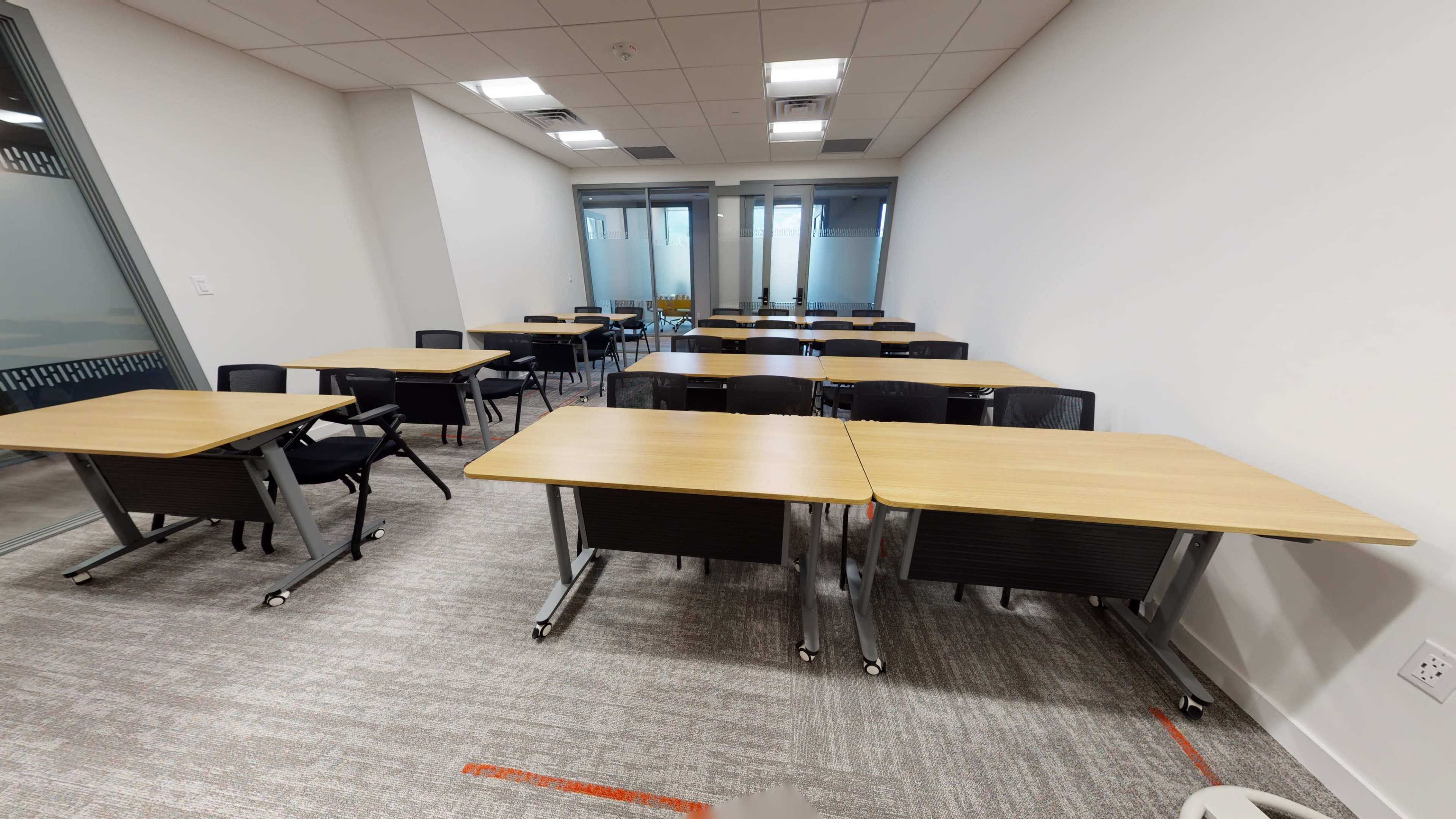 A classroom setting with several empty desks arranged in rows facing the front.