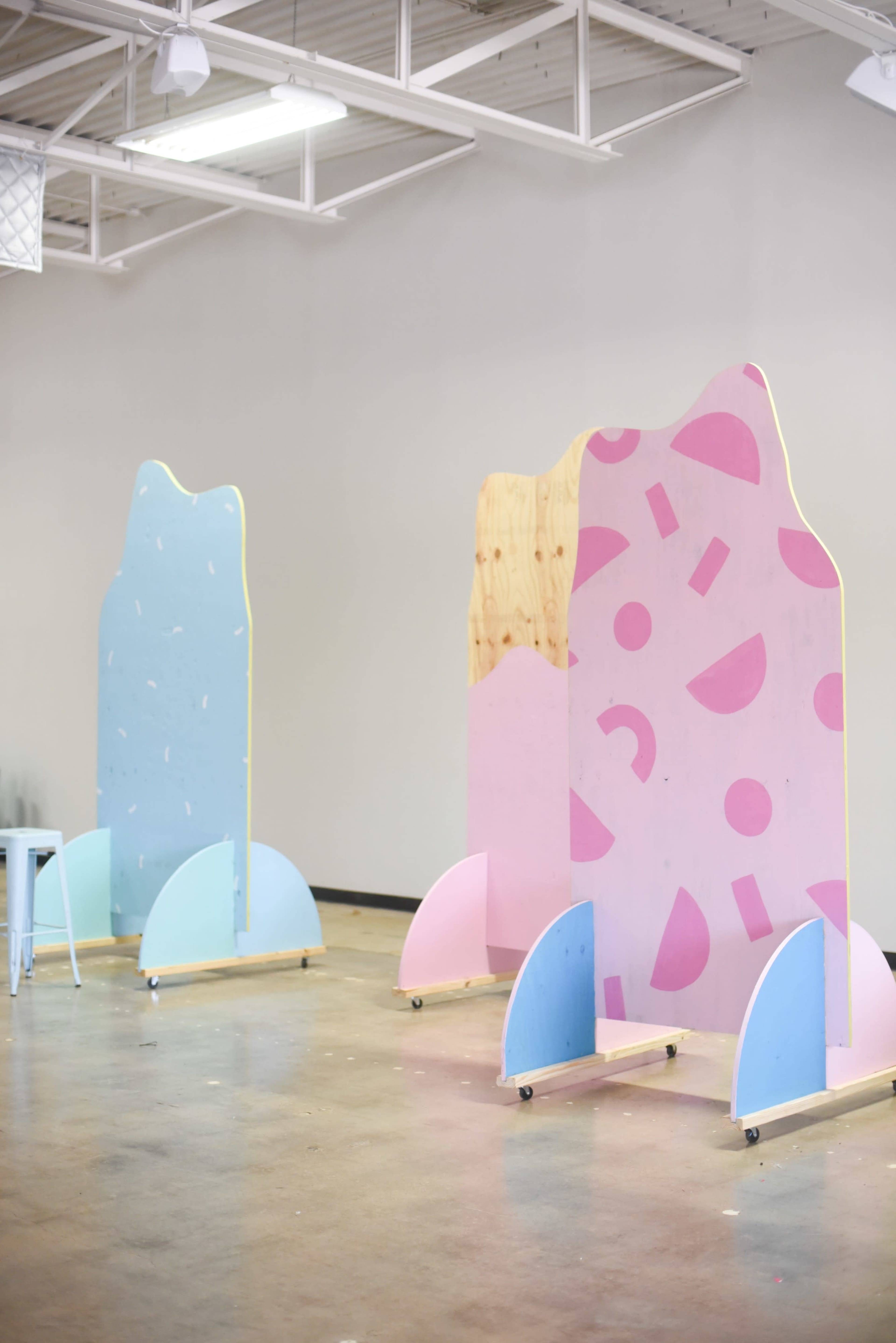 Three colorful partitions in a spacious, well-lit room designed with pastel blue and pink patterns.