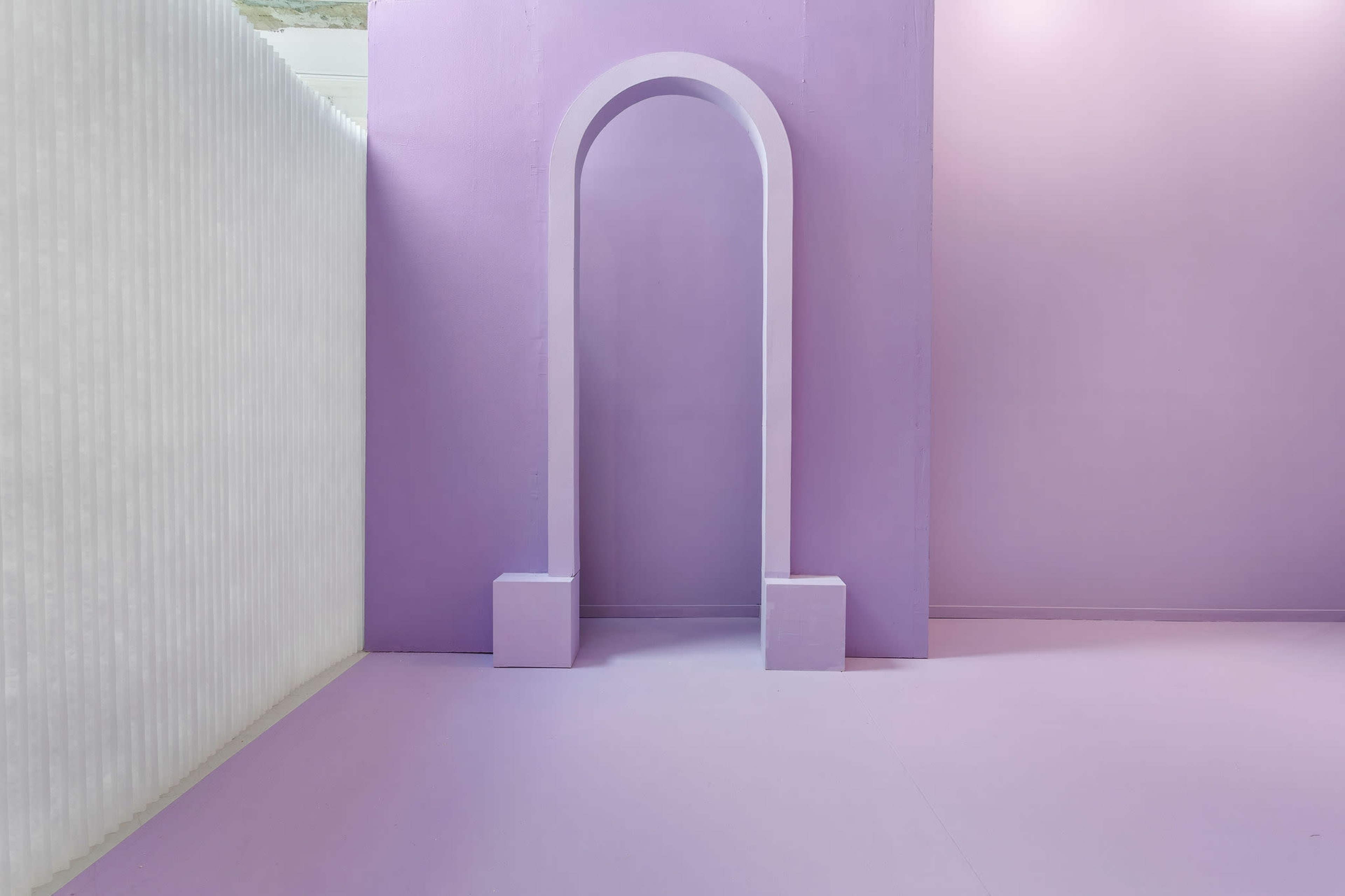 A minimalistic interior space featuring a large archway and smooth purple walls and floor.