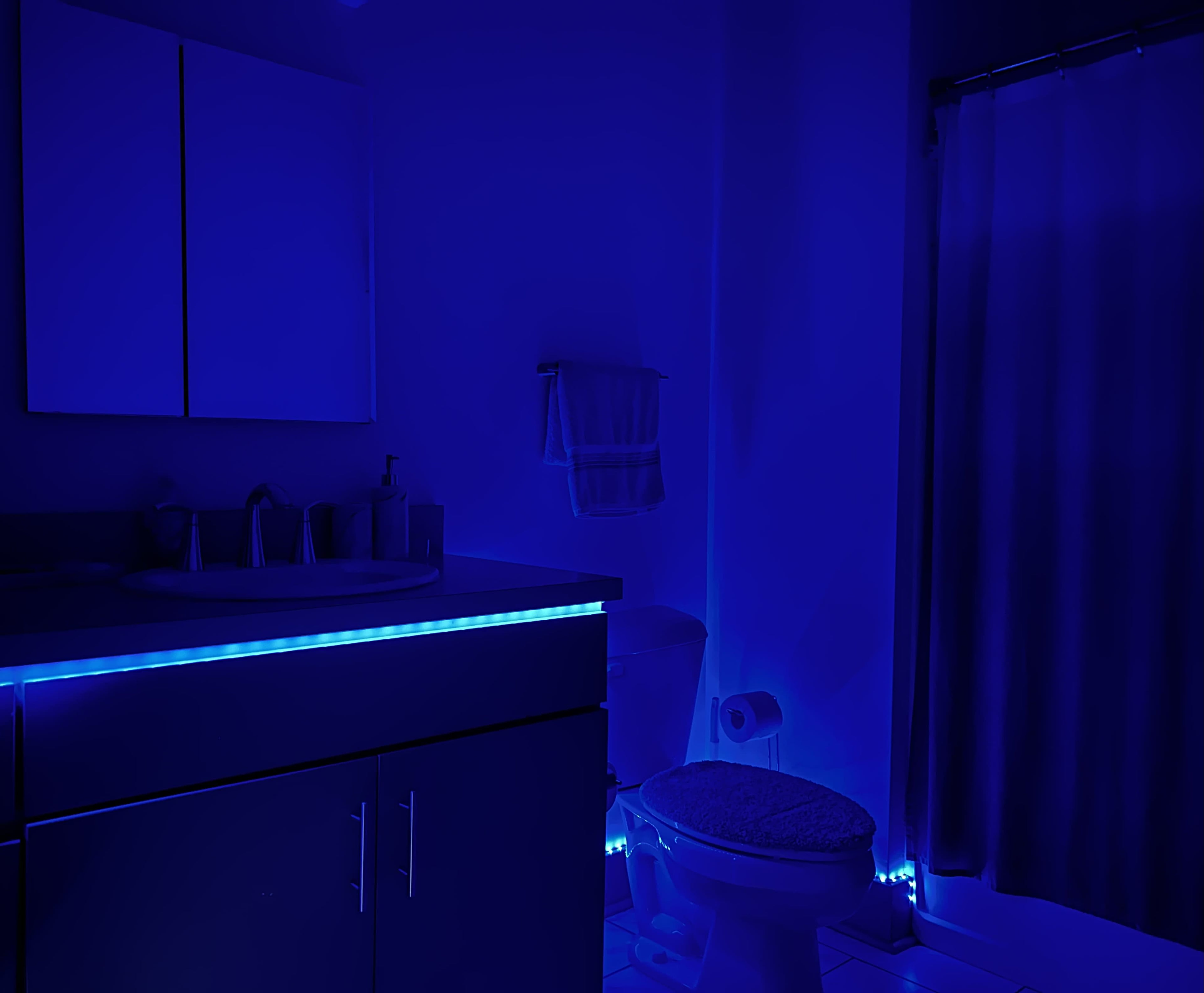 The bathroom features blue LED lighting illuminating the countertop and the base of the toilet.