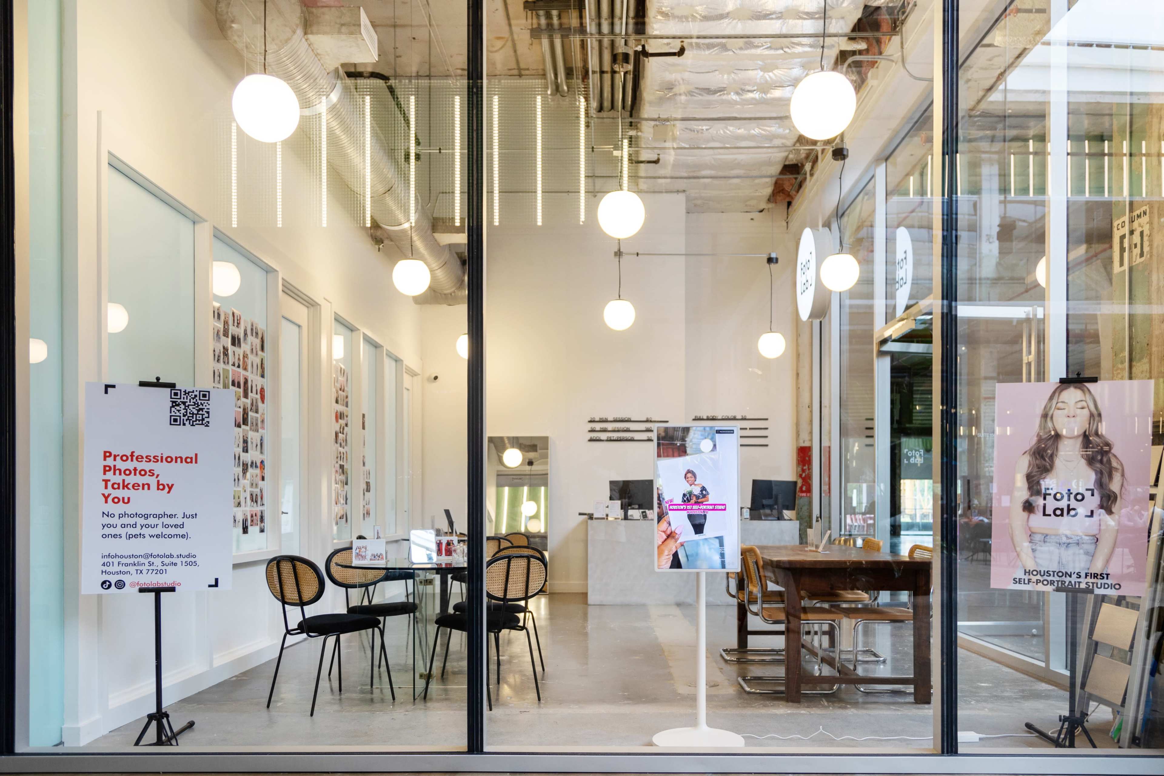 A modern photography studio features a large window with signage and various photo displays inside, along with tables and chairs for client consultations.
