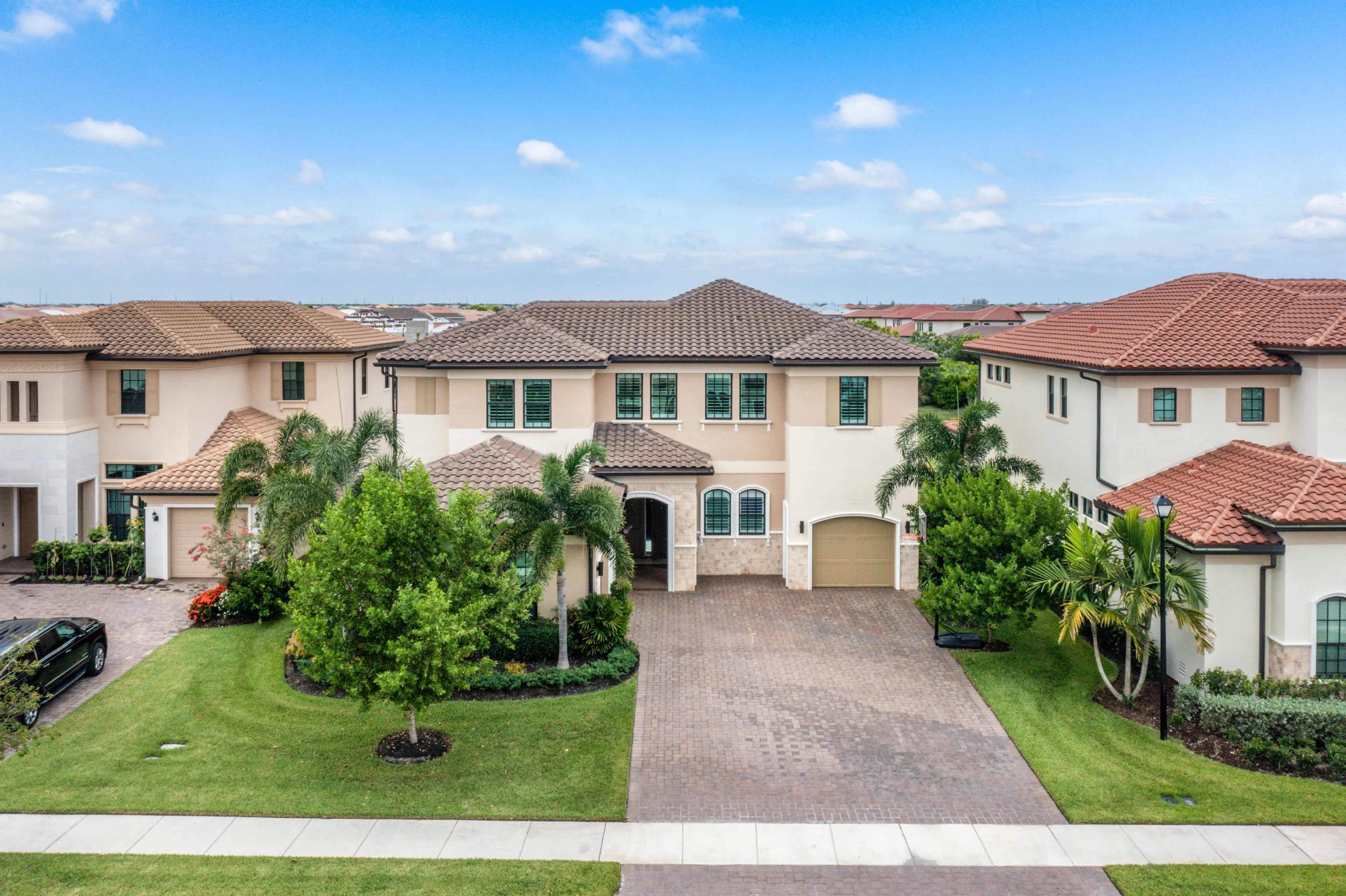 A two-story house with a tile roof and landscaped yard is situated in a suburban neighborhood.