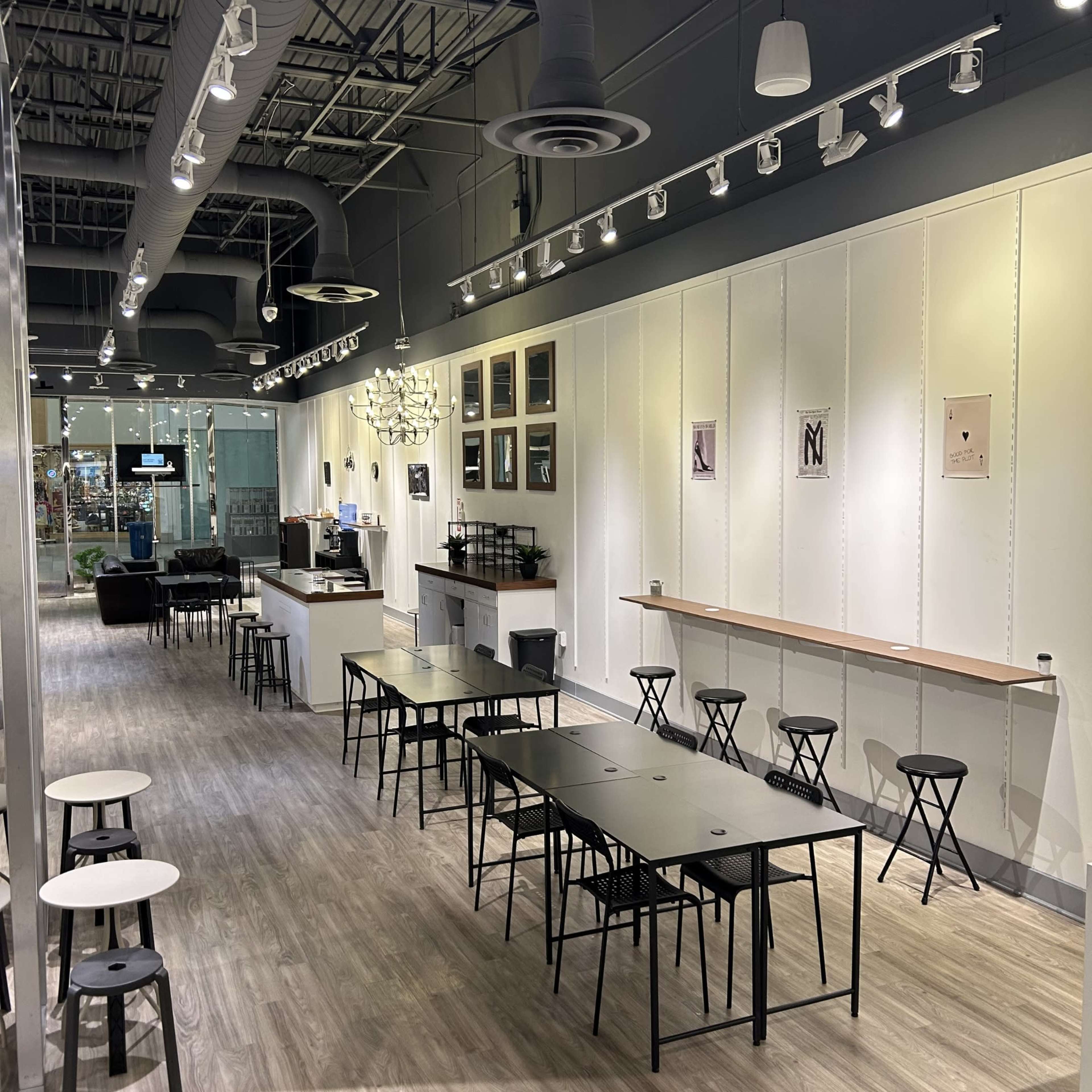 The image shows a sleek, modern interior of a café with minimalist decor, featuring several tables, chairs, and a counter area at the back.