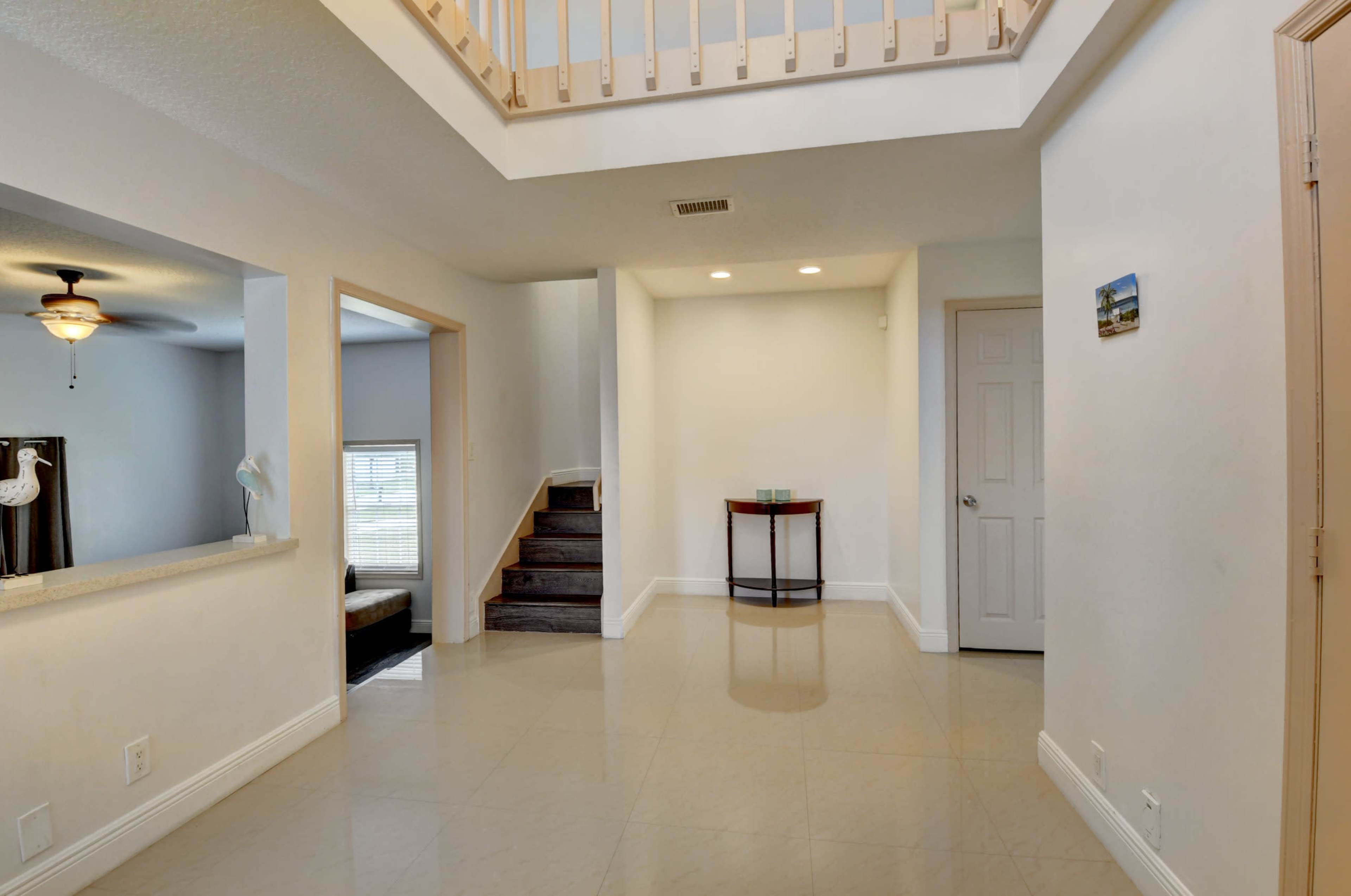 A spacious foyer features a staircase leading to an upper level, with a small table against a wall and an open view to the adjacent living area.