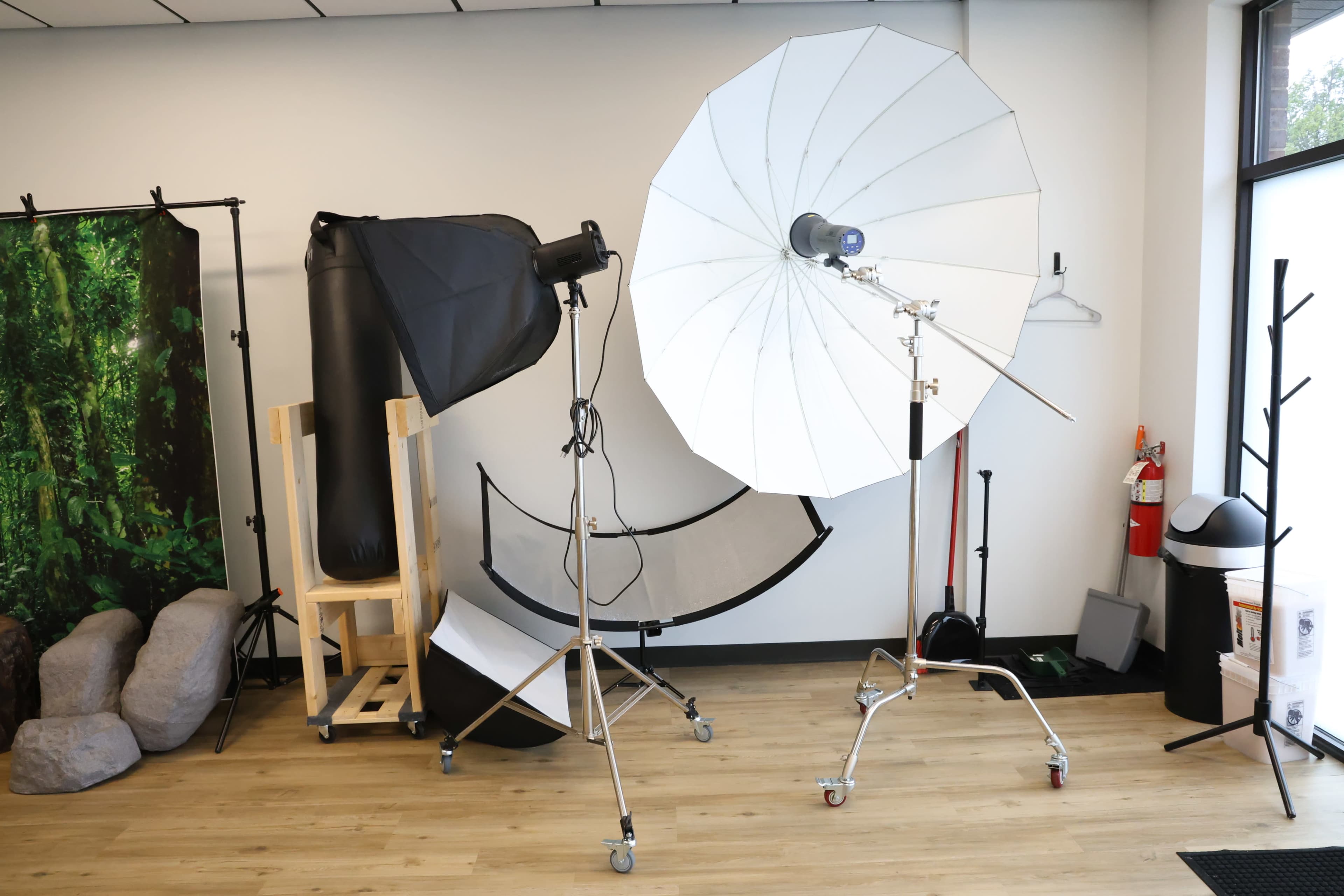 A photography studio setup featuring lighting equipment, backdrop stands, and various props arranged on a wooden floor.