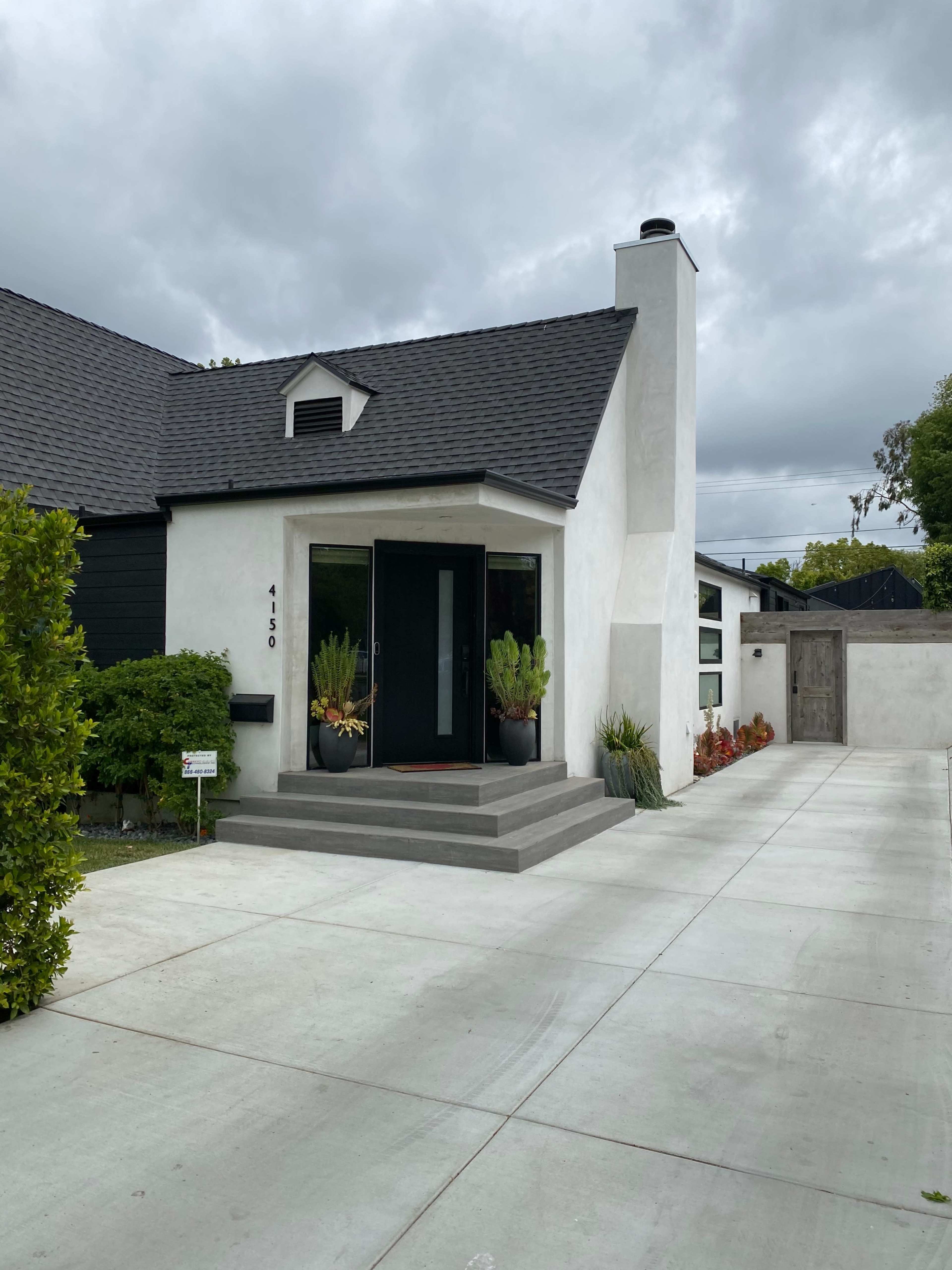 A modern house with a flat entrance, a large front door, and a neatly paved driveway.