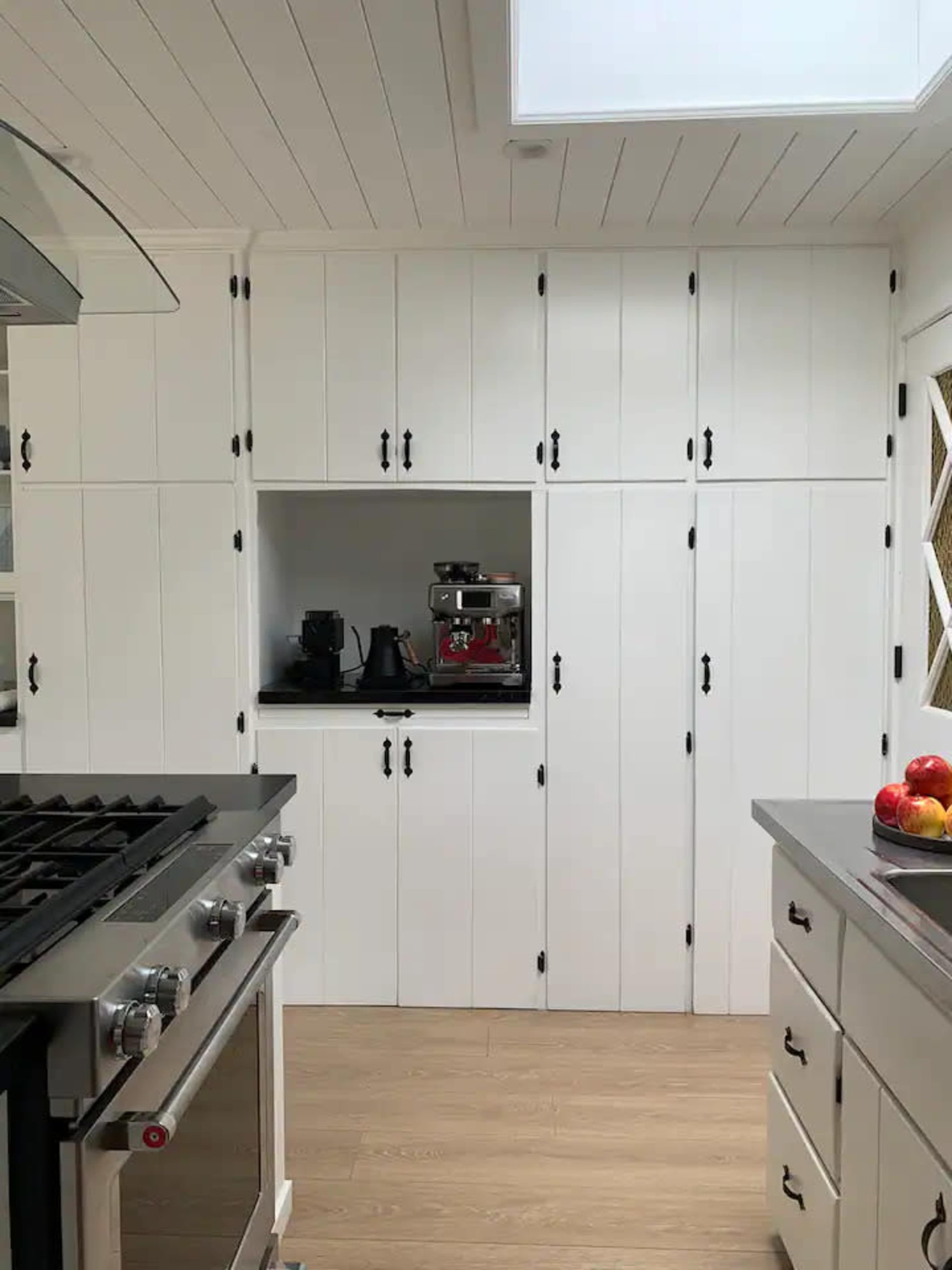 A modern kitchen with white cabinetry, a stainless steel stove, and an area designated for small appliances.