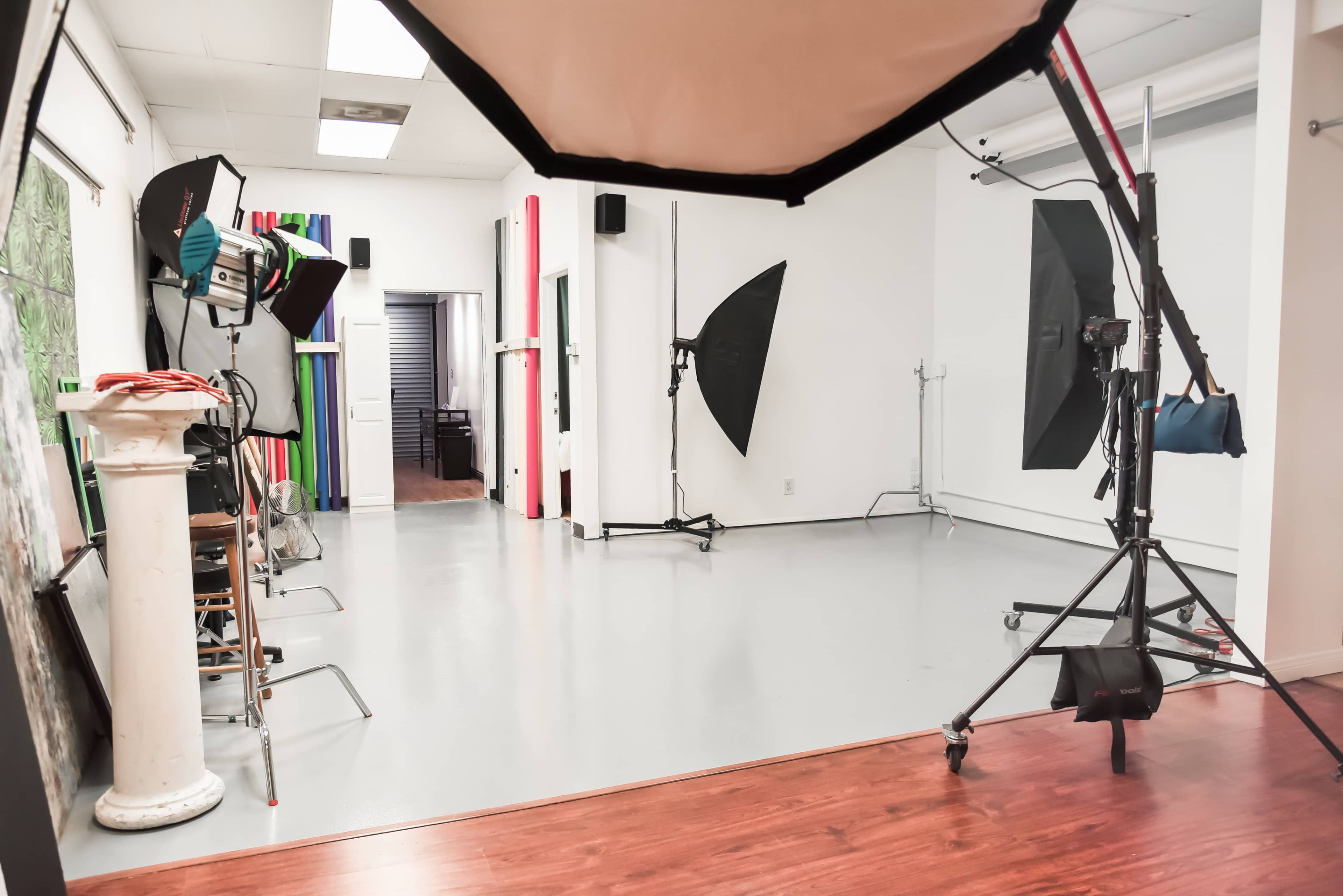 A photography studio featuring various lighting equipment, stands, and backdrops on a polished floor.