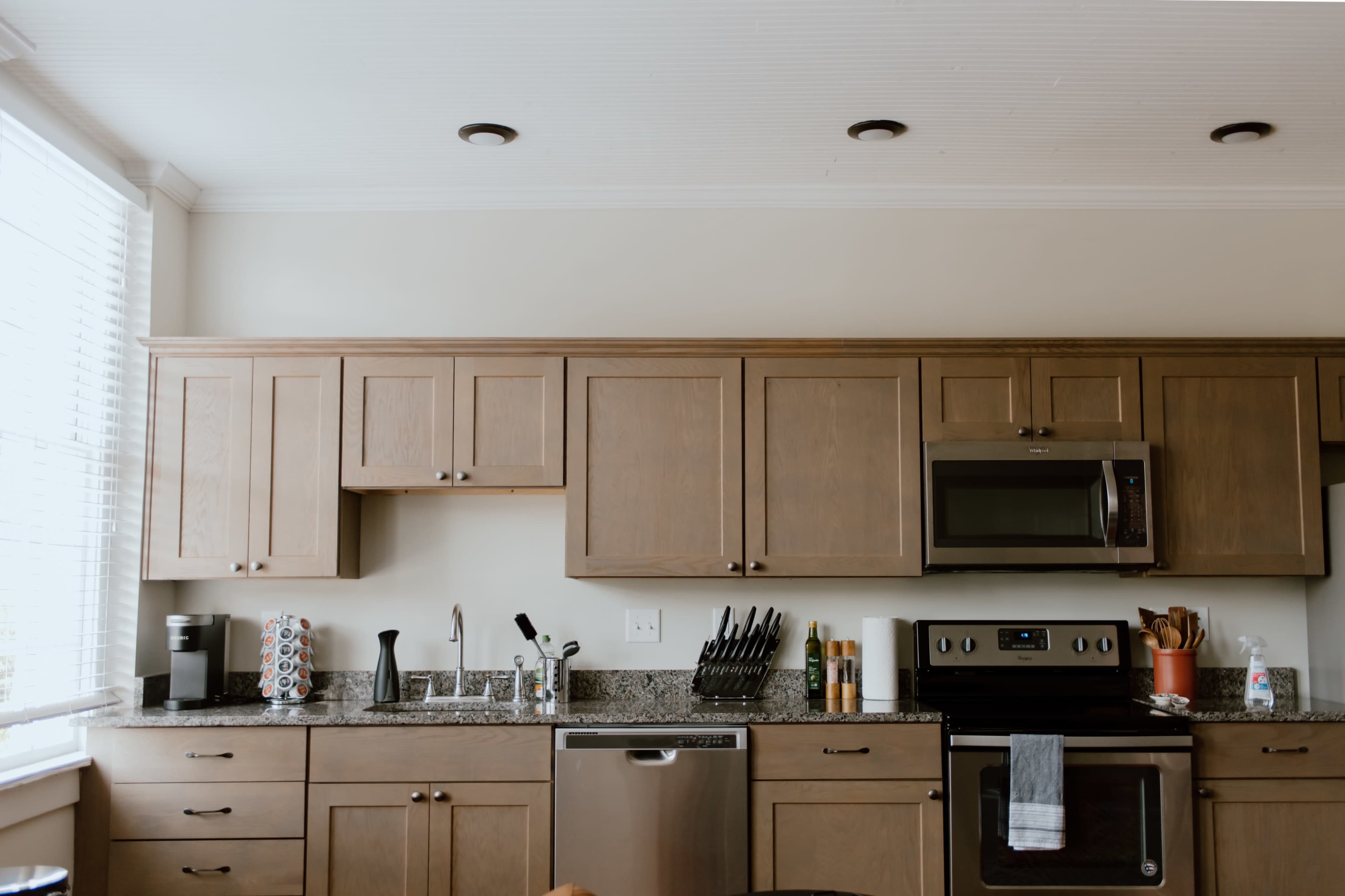 A modern kitchen with wooden cabinetry, a stainless steel microwave, and granite countertops.