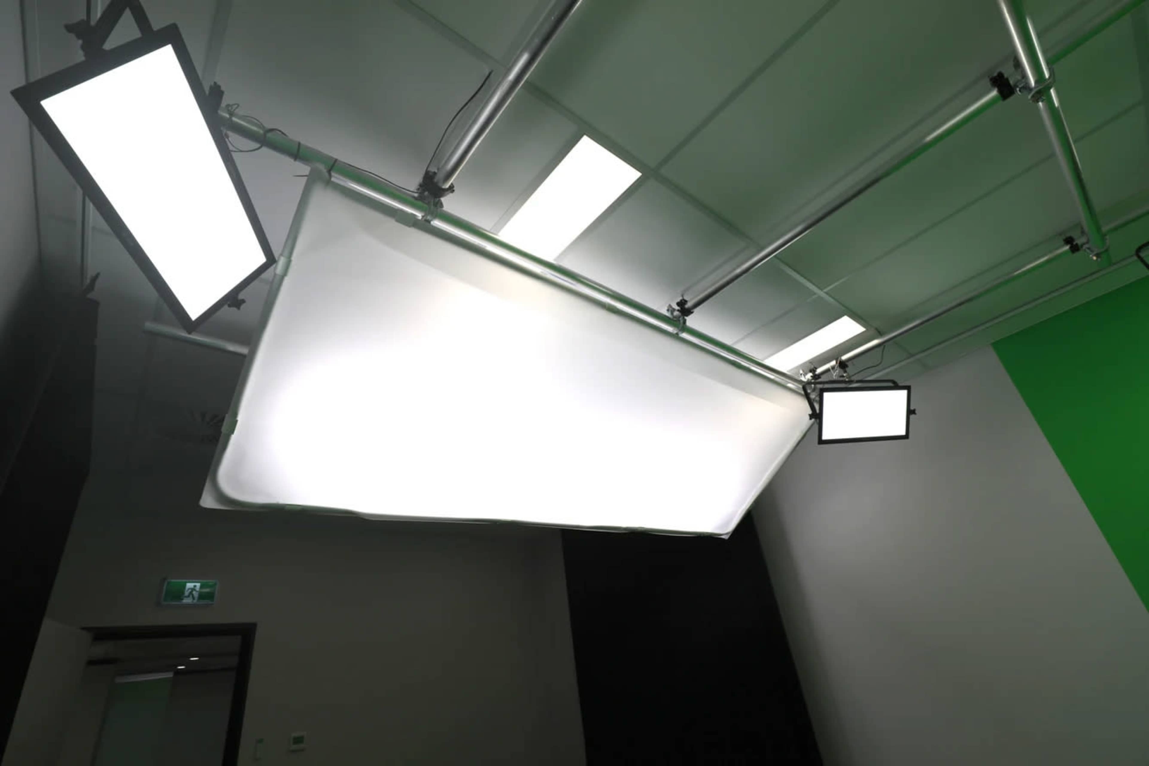 The image shows a ceiling setup with fluorescent lights and a large white backdrop in a studio environment.