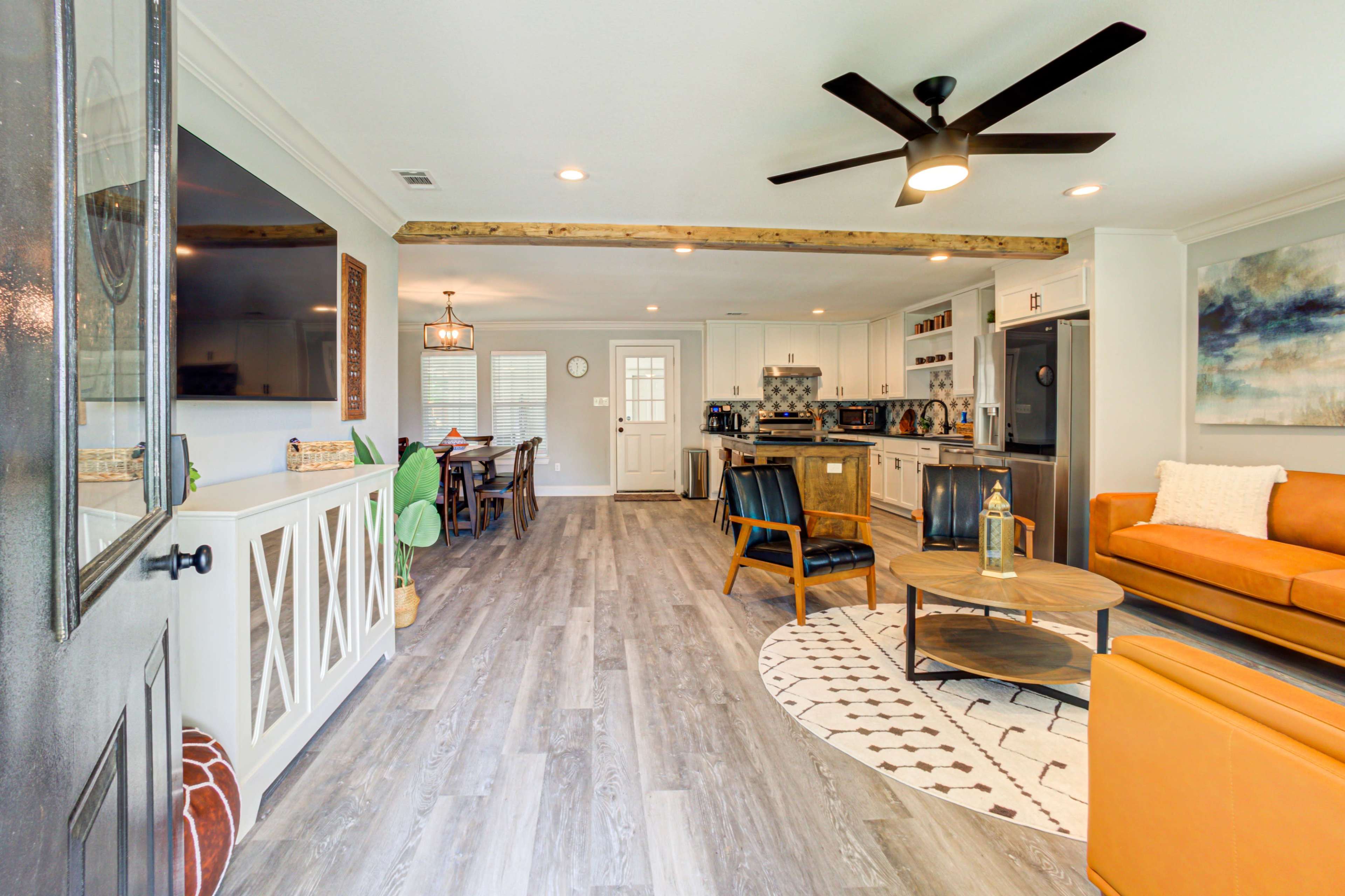 A modern open-concept living space featuring a kitchen, dining area, and lounge with a mix of contemporary furnishings and wooden accents.
