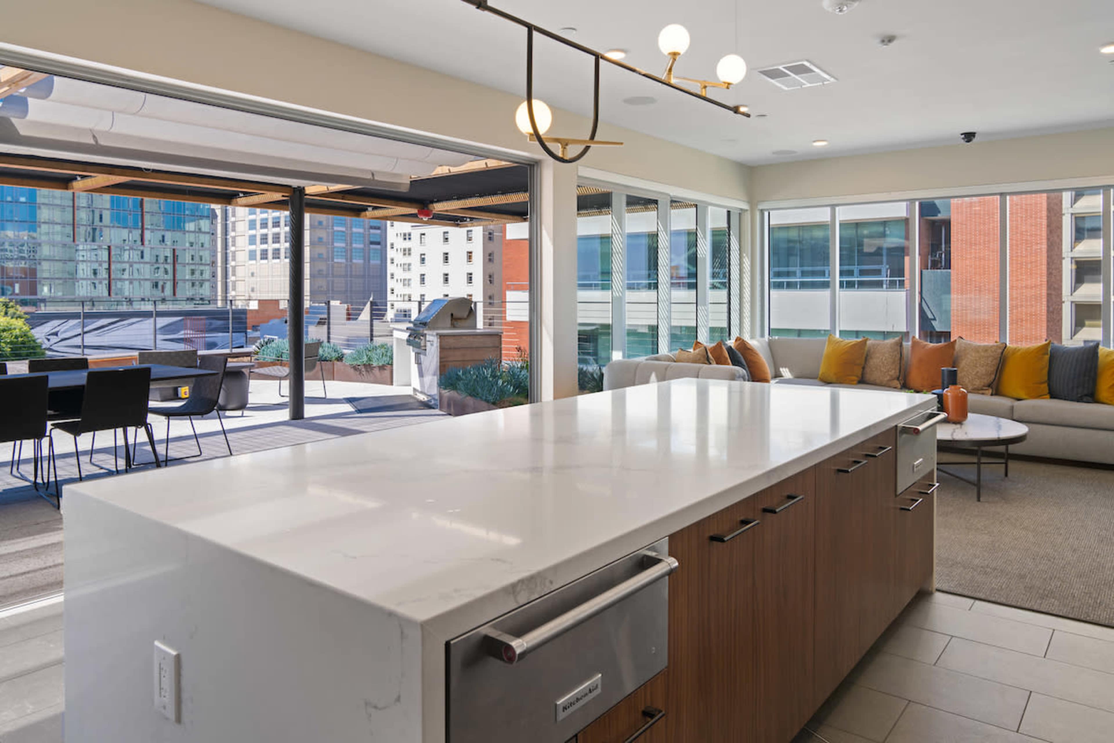 A modern kitchen with a large island and a view of an outdoor patio area through expansive windows.