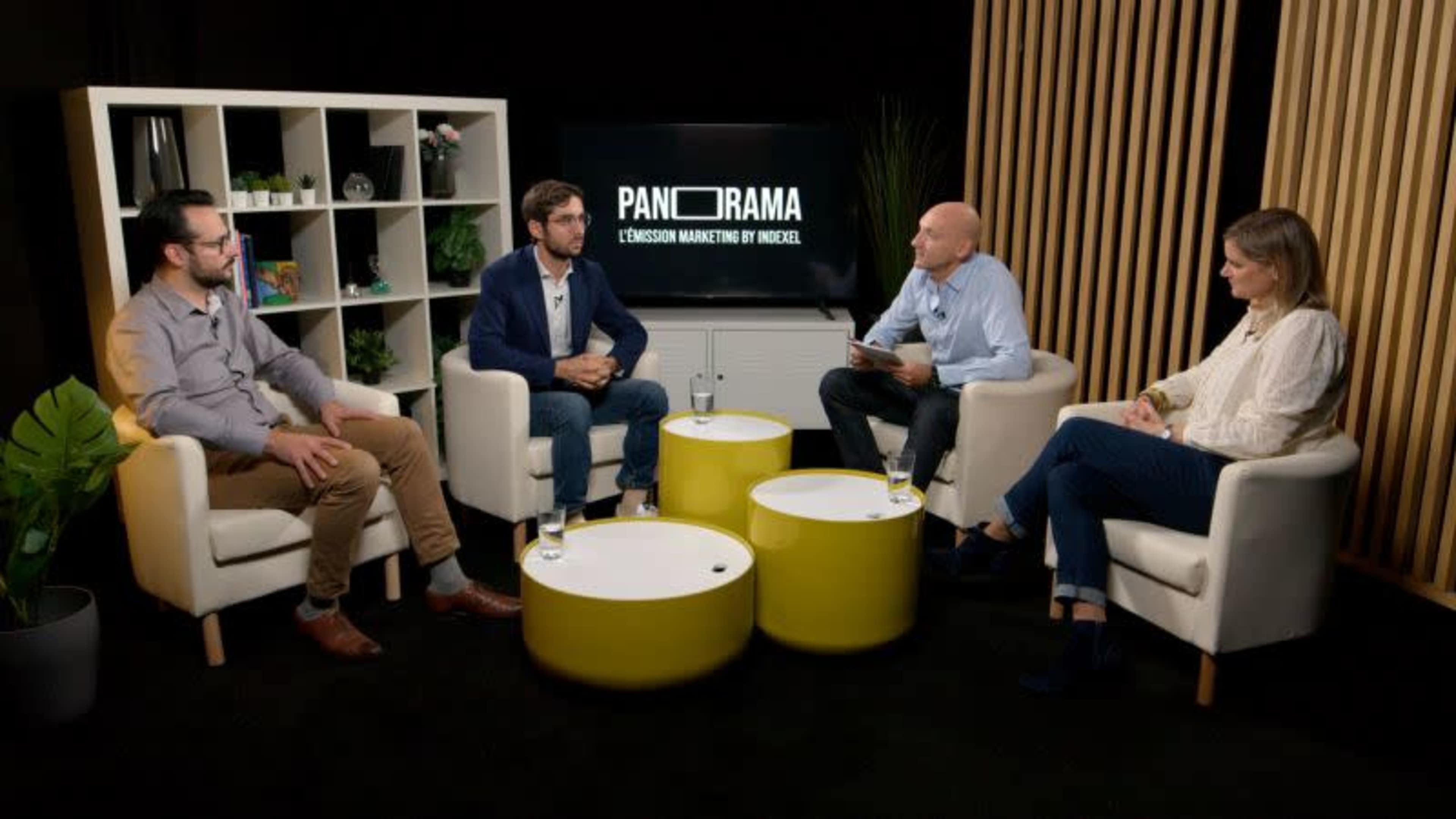 A group of four people seated around small tables in a modern studio setting, participating in a discussion on marketing.