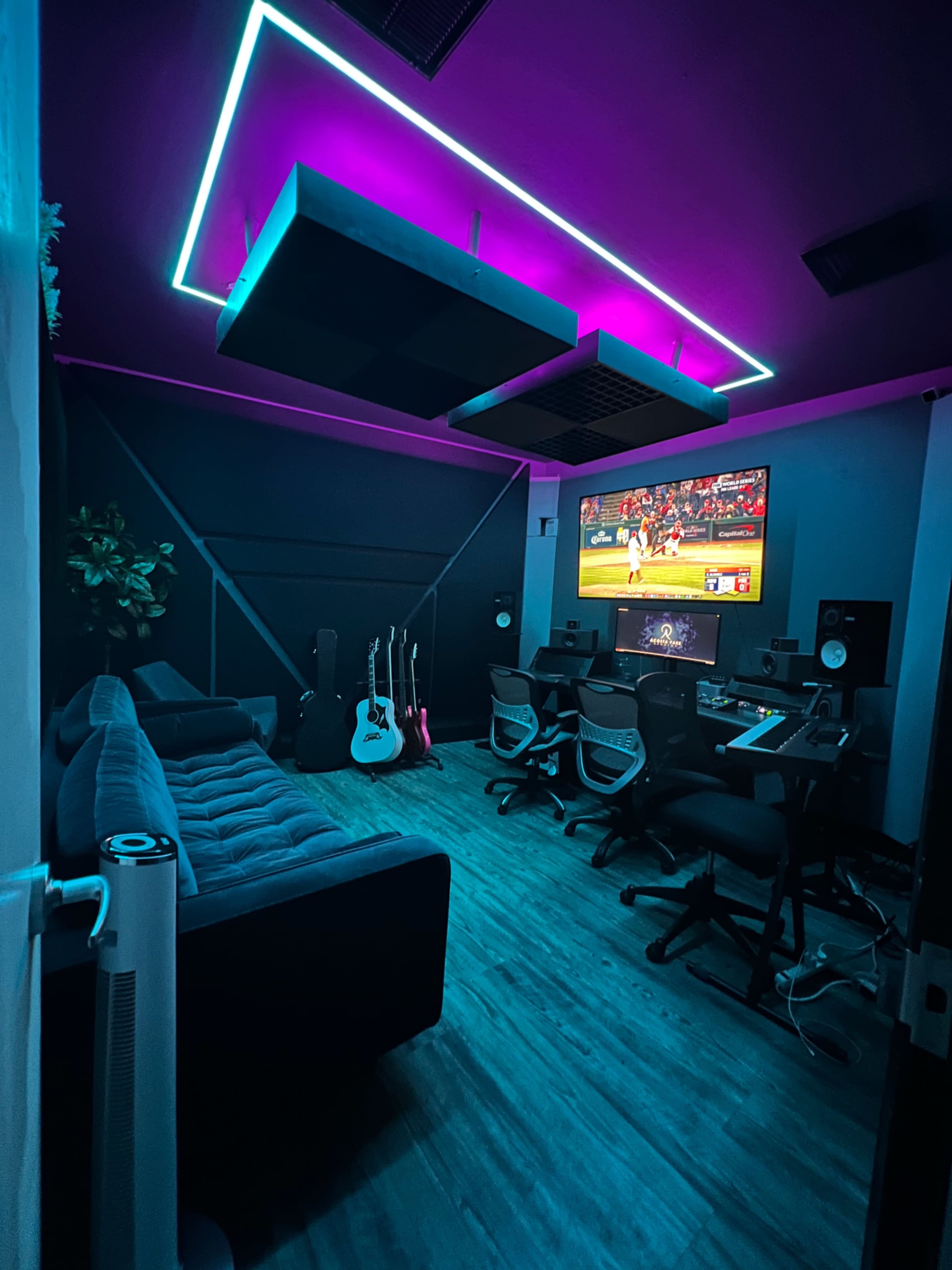 A modern room features a television displaying a sports game, surrounded by stylish furniture, musical instruments, and dynamic LED lighting.