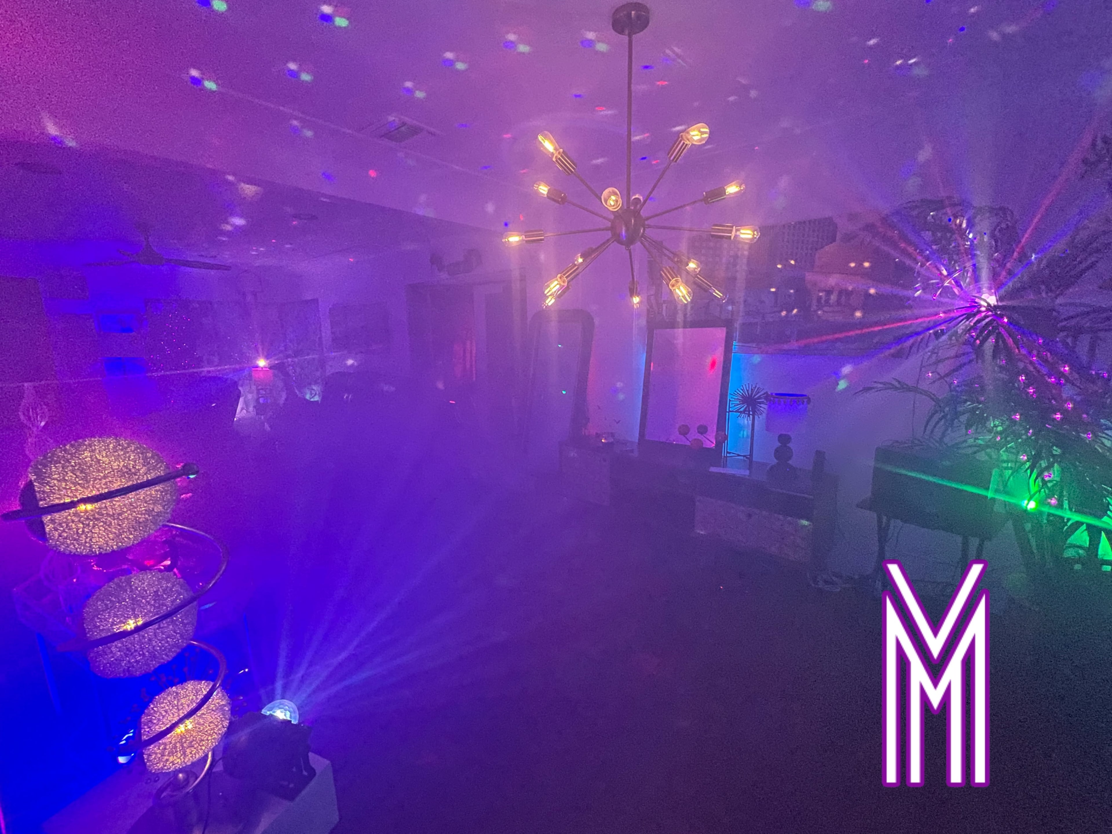 The interior of a room is filled with colorful lights and projections, creating a vibrant, party atmosphere.