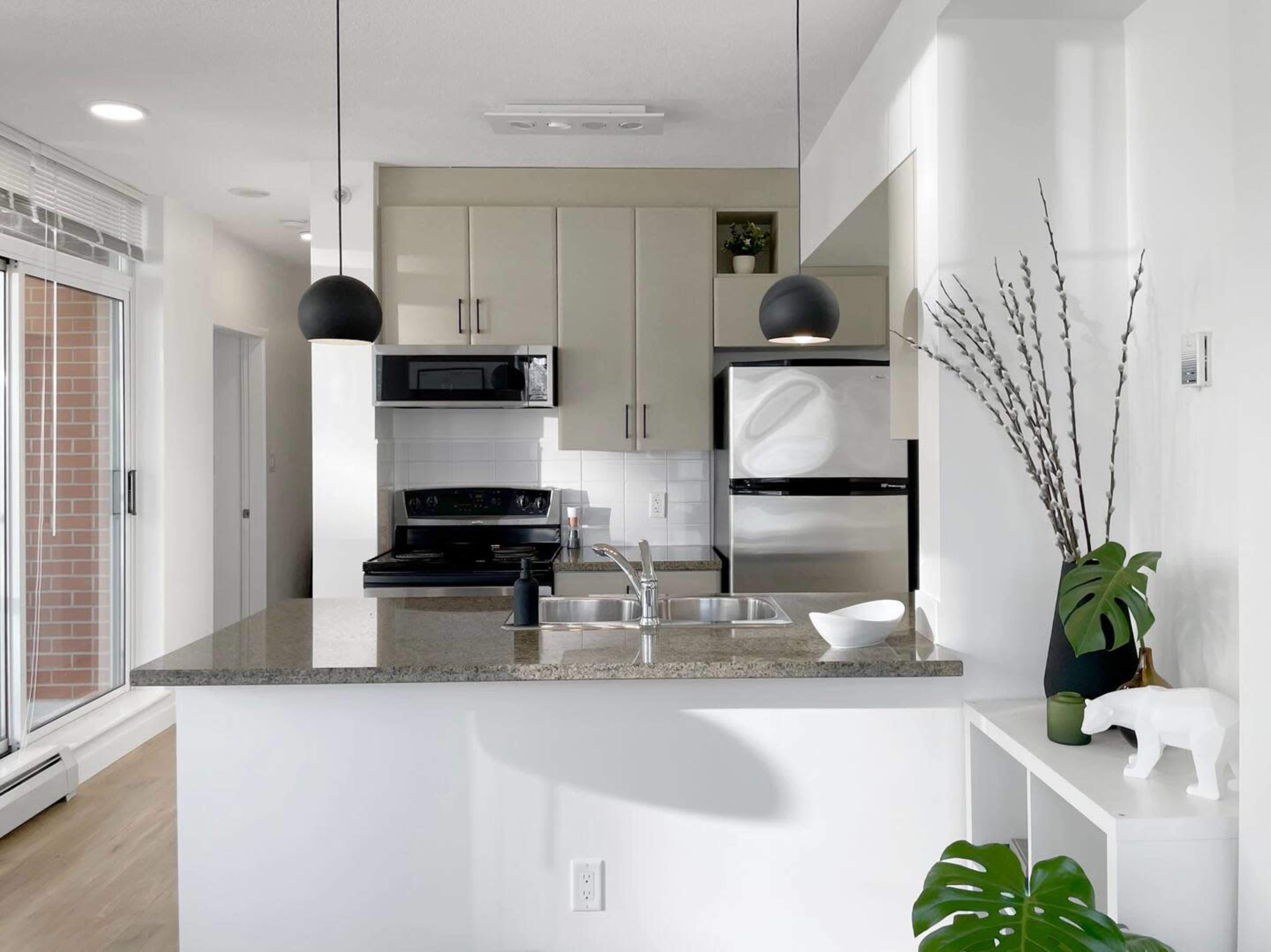 A modern kitchen features granite countertops, stainless steel appliances, and pendant lighting above the island.