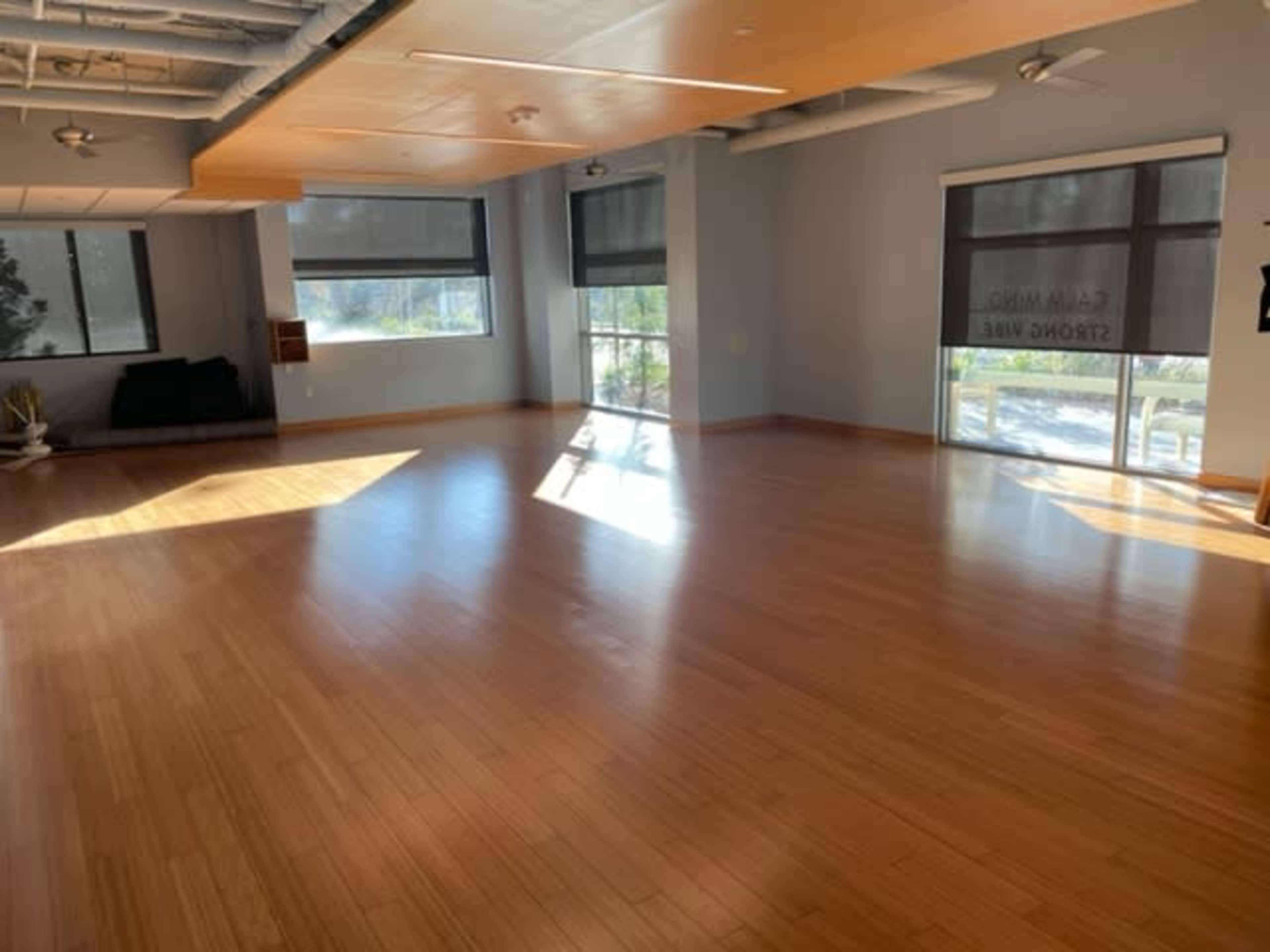 A spacious room with bamboo flooring and large windows letting in natural light.