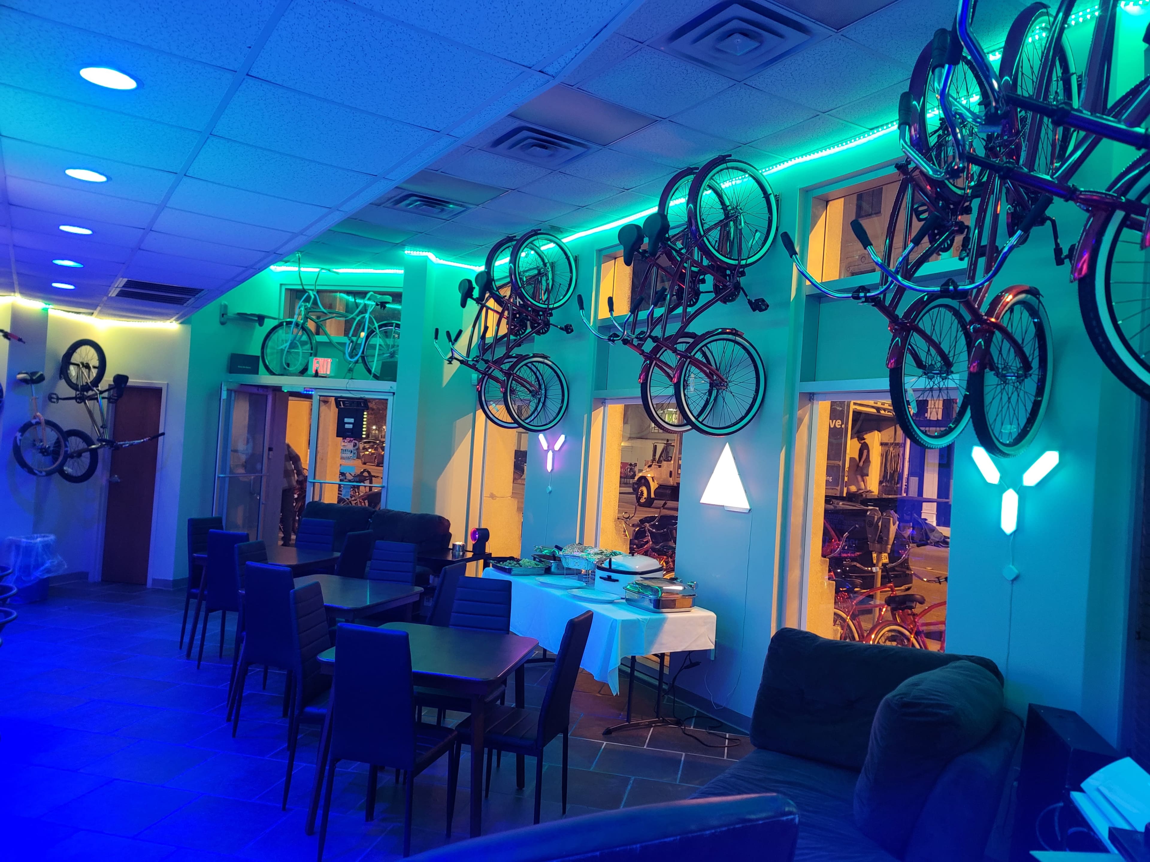 The interior of a brightly lit café features bicycles mounted on the walls and tables set for dining.