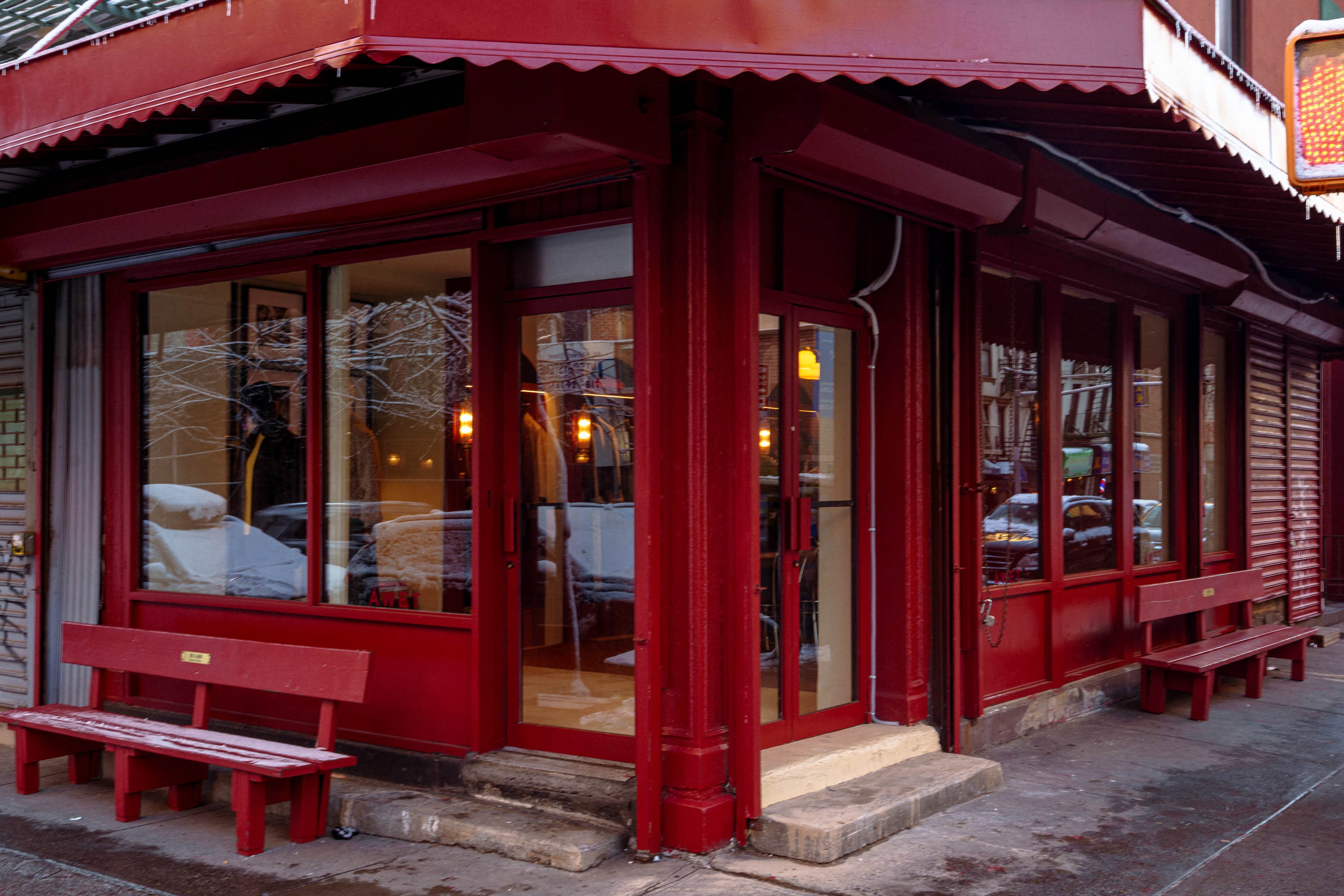 The image shows the exterior of a red-painted restaurant with large glass windows, located on a street corner.