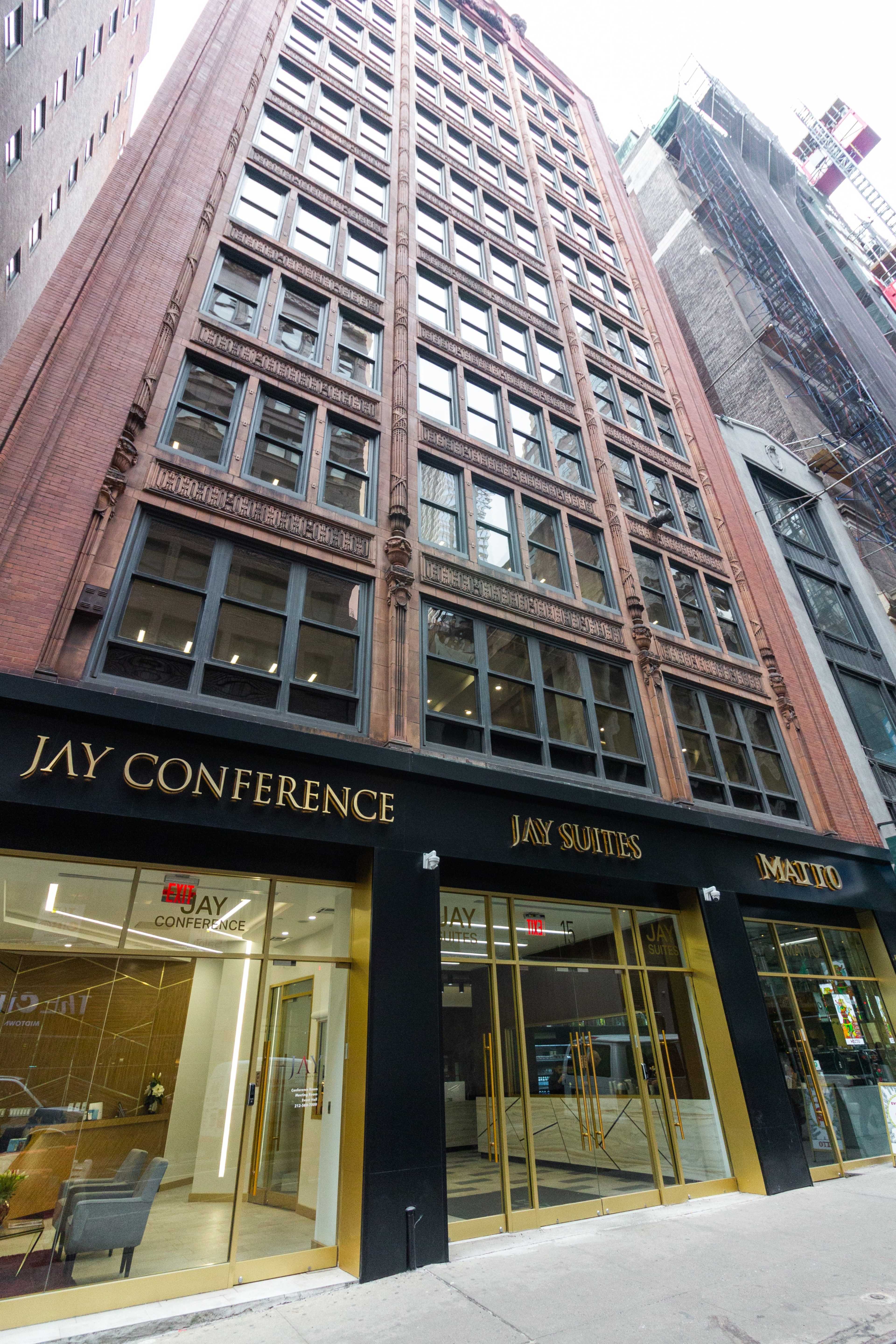 The image shows a tall, modern building with a sleek entrance featuring the names "JAY CONFERENCE," "JAY SUITES," and "MATRIO" prominently displayed.
