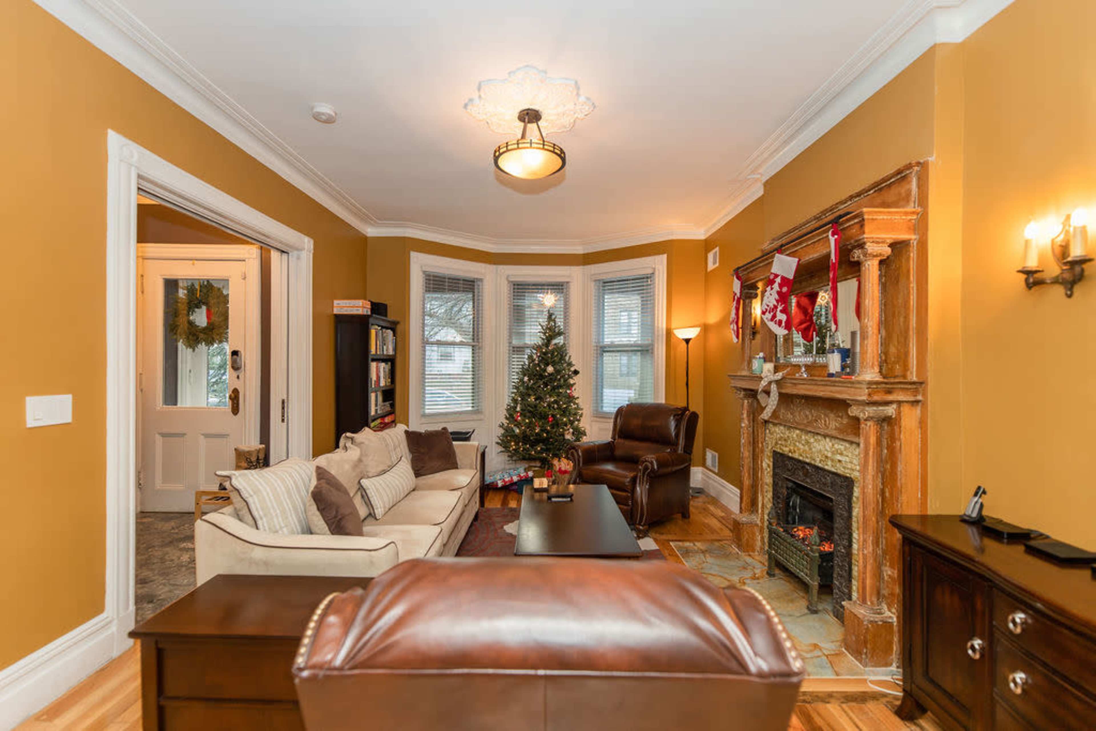 The living room features a Christmas tree, a fireplace decorated with stockings, and a seating area with a sofa and recliners.