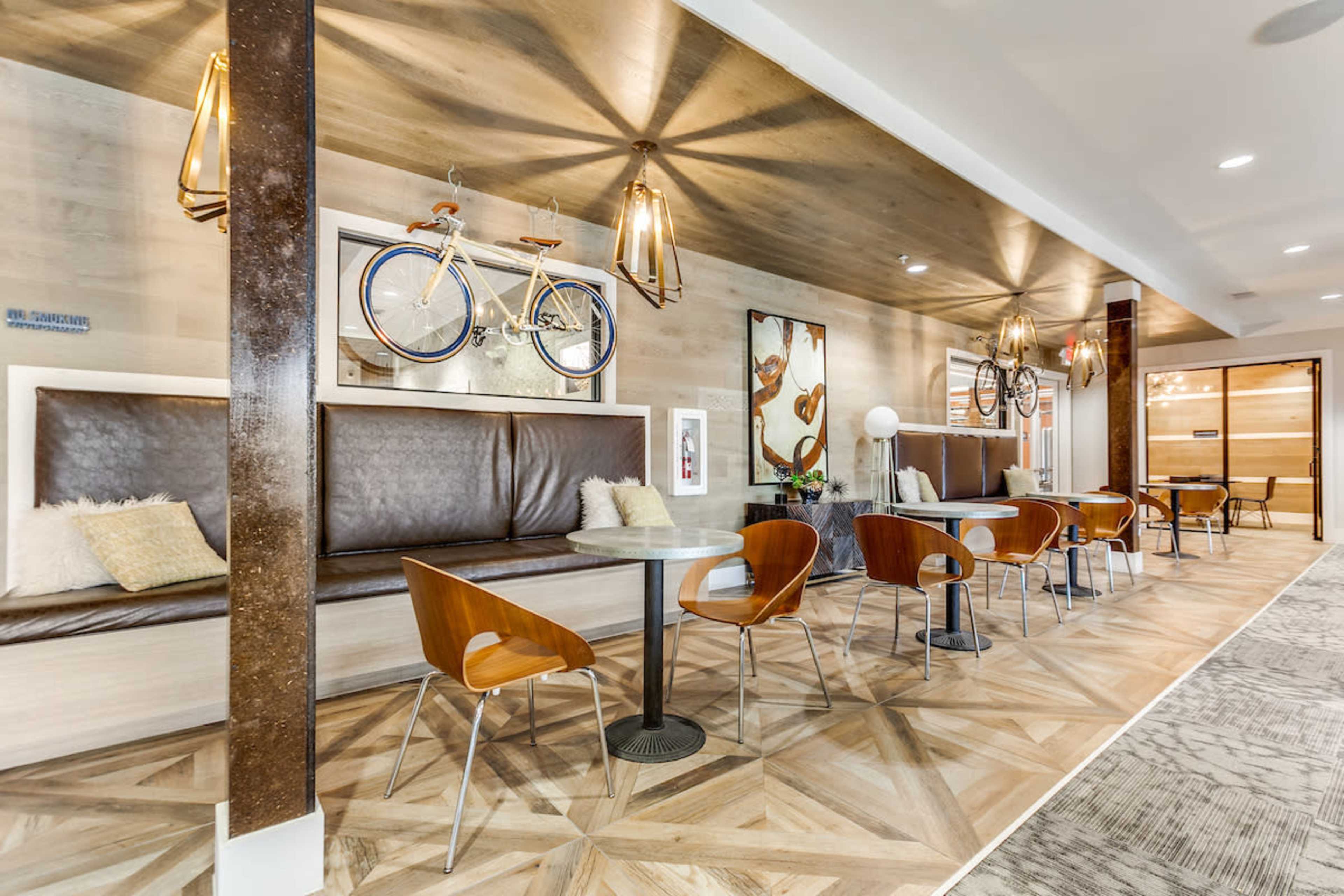 A modern interior space with wooden seating areas, tables, and decorative bicycle art on the walls.