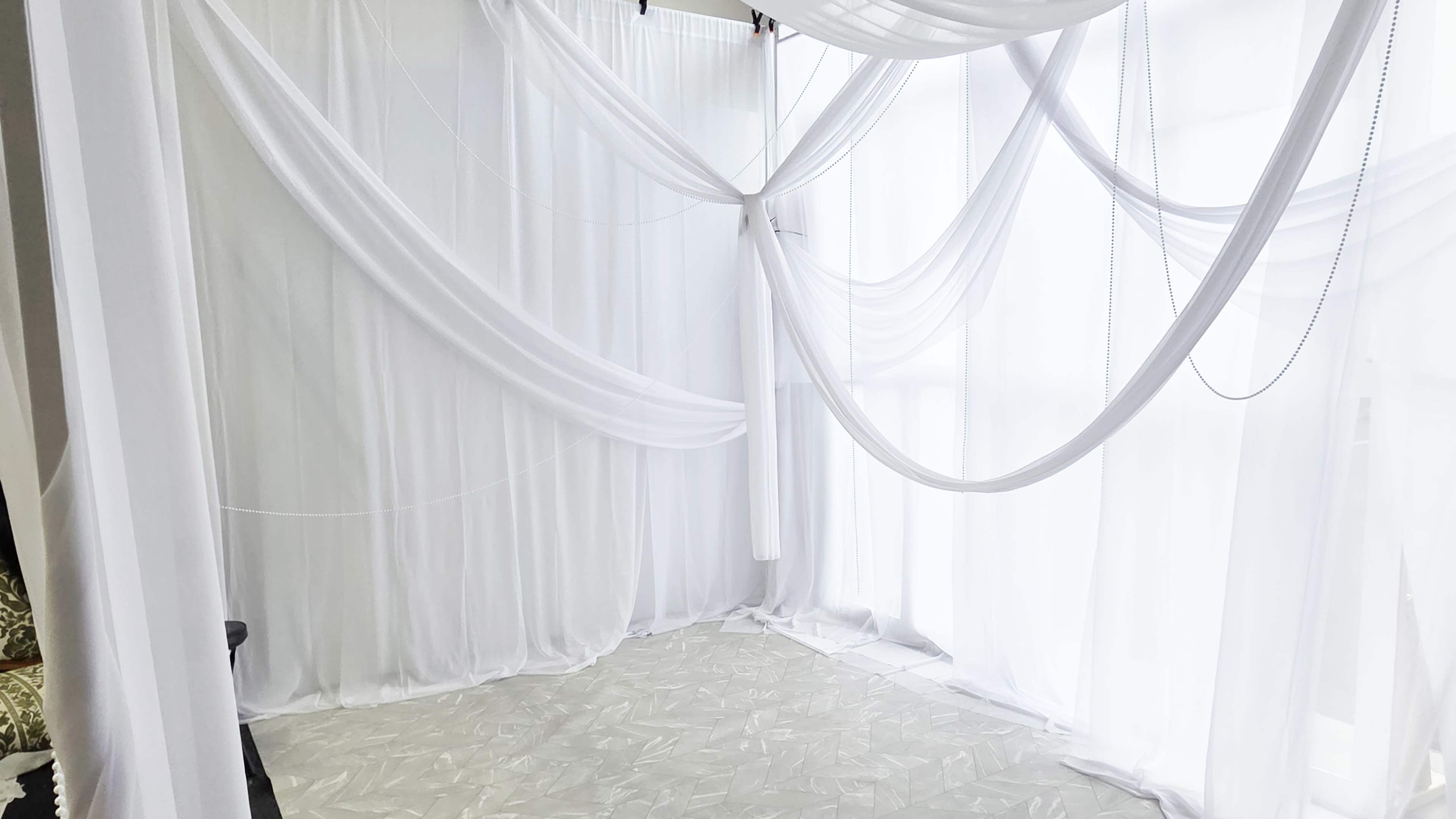 The image features a bright, airy space decorated with flowing white fabric draped across the walls and ceiling.