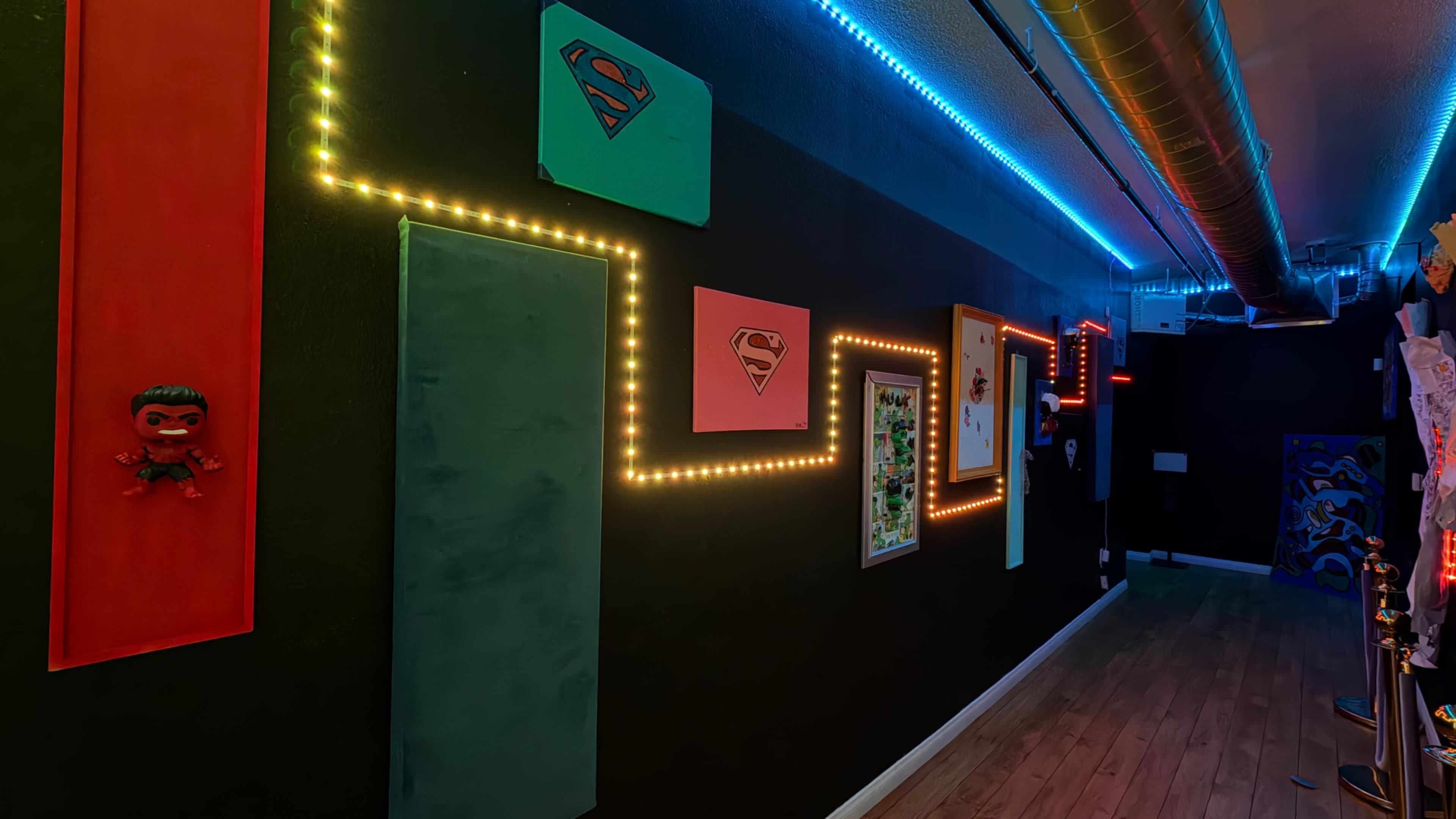 The image shows a dimly lit hallway decorated with colorful wall panels and illuminated with LED lights.