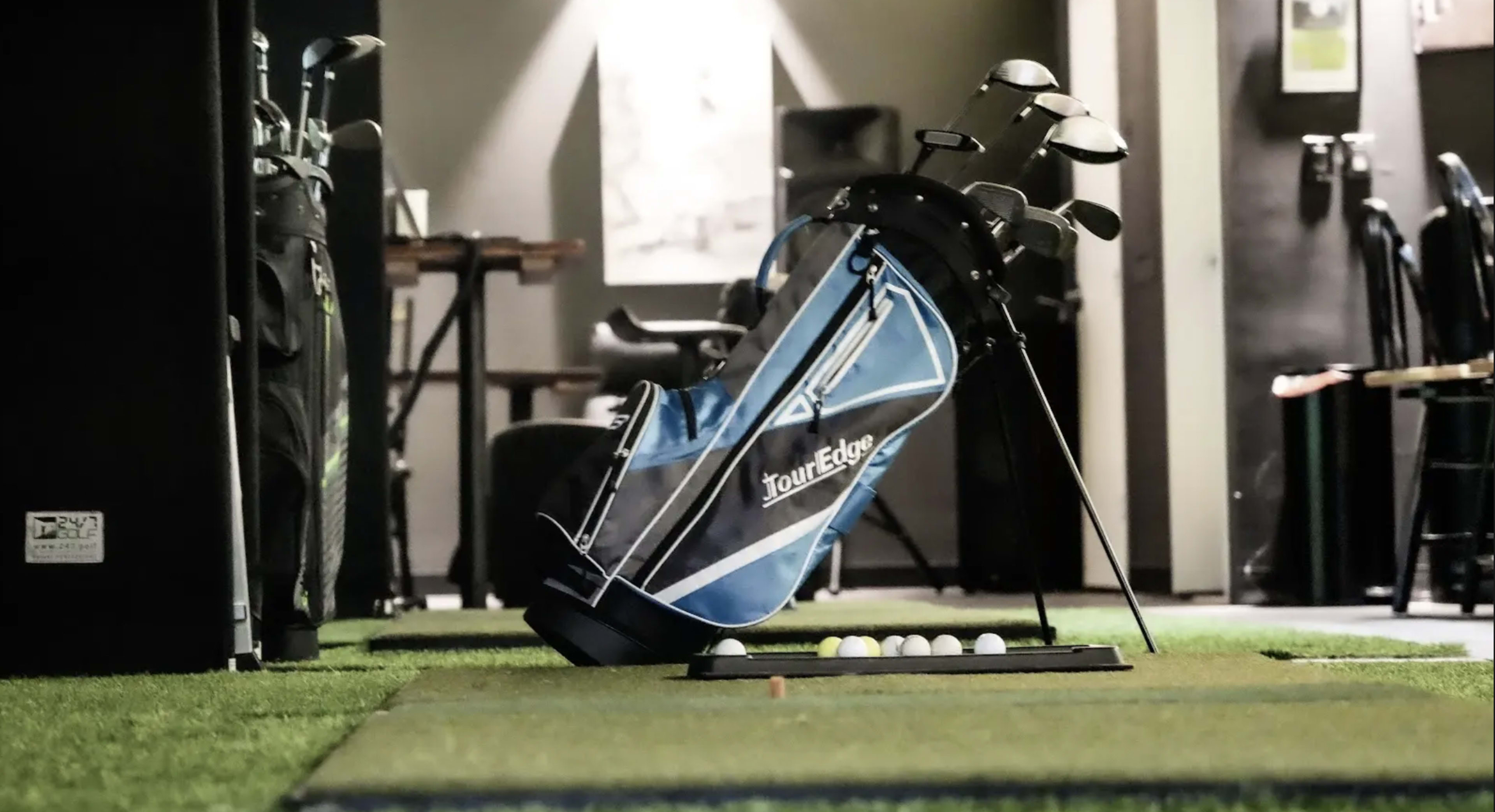 A golf bag is leaning against a stand near a practice area with golf balls arranged on the ground.