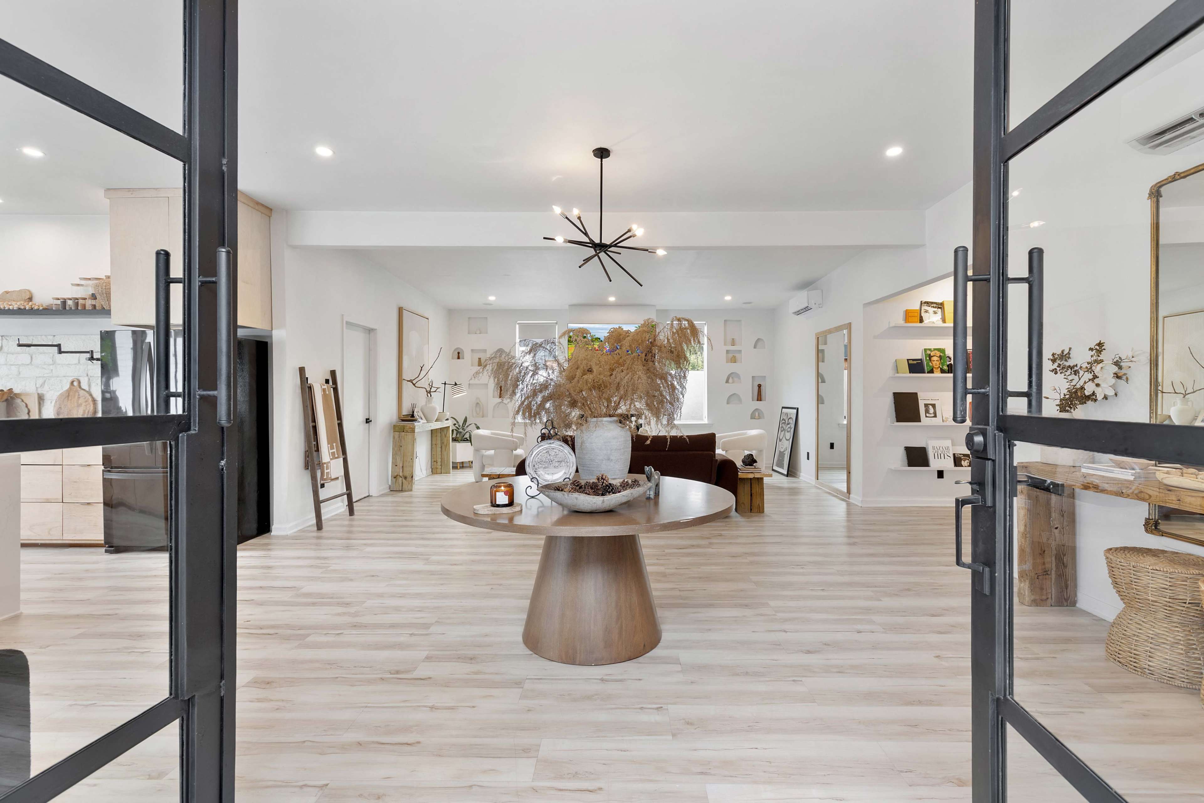 A modern entryway features double glass doors opening to a spacious living area with a round table and decorative elements.