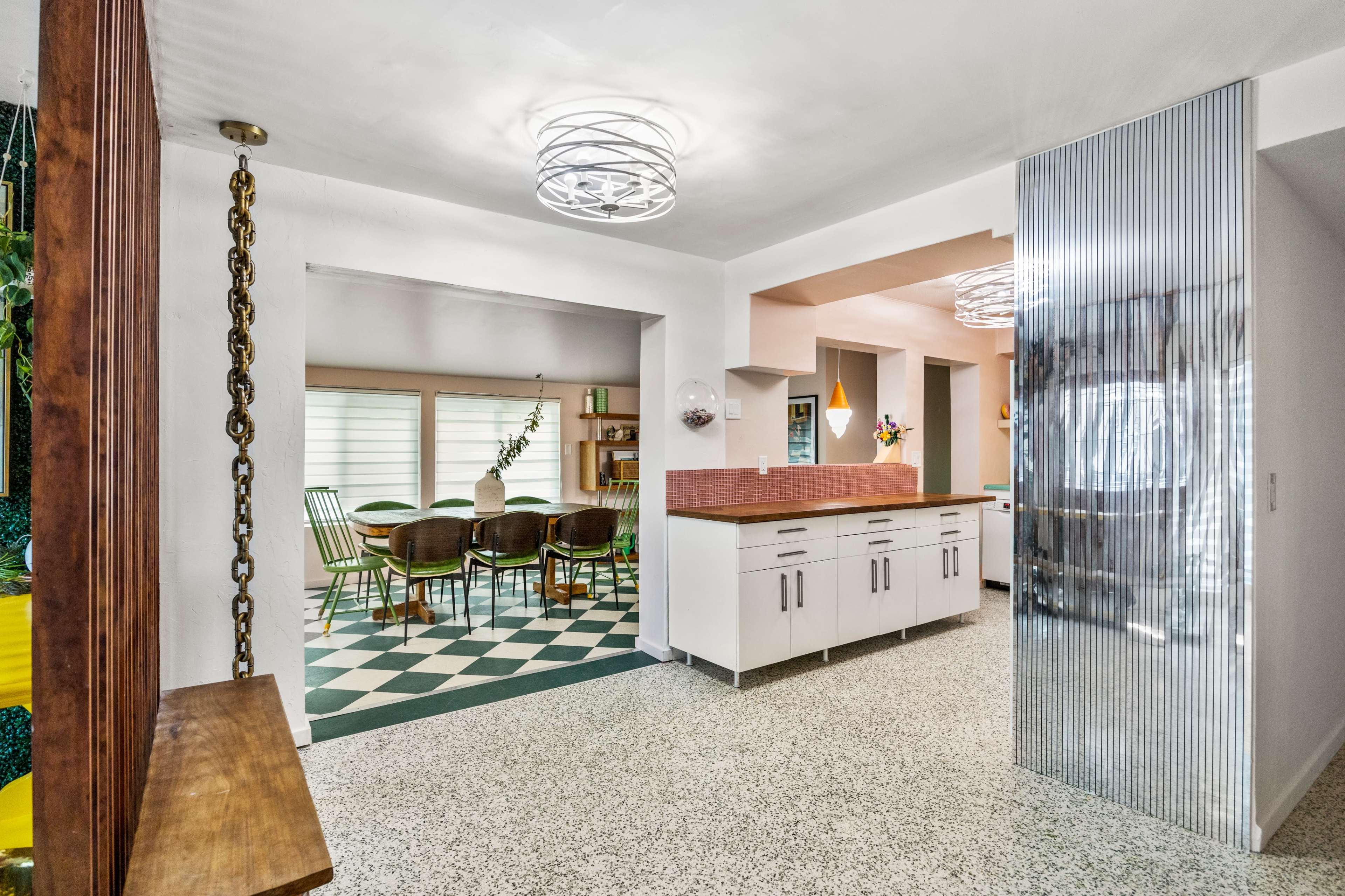 The image shows an open-concept kitchen and dining area with a checkered floor and modern lighting fixtures.
