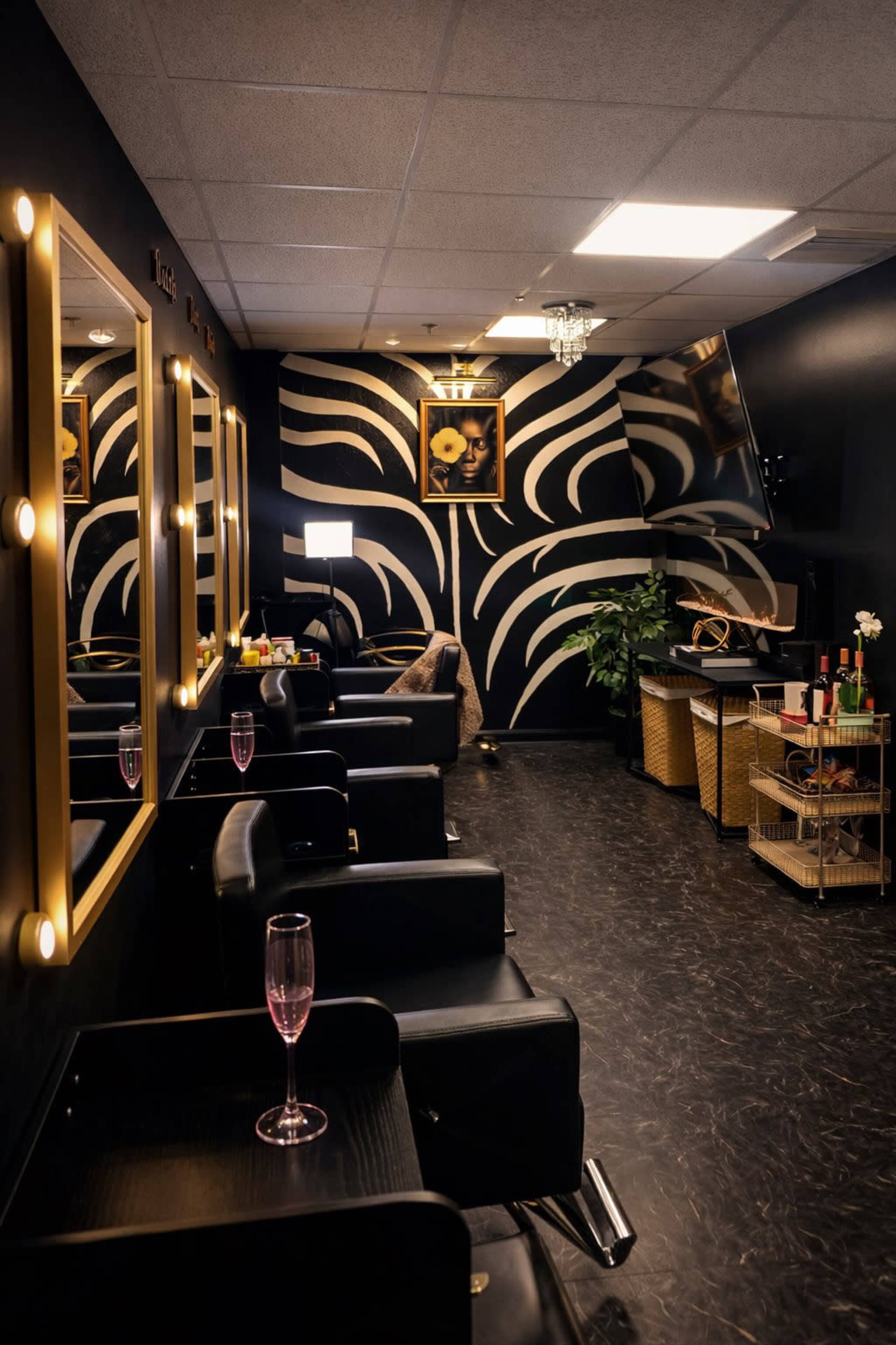 The image shows a stylish salon with black walls featuring a bold wave design, equipped with glam mirrors and black chairs, along with a drink station and a television.