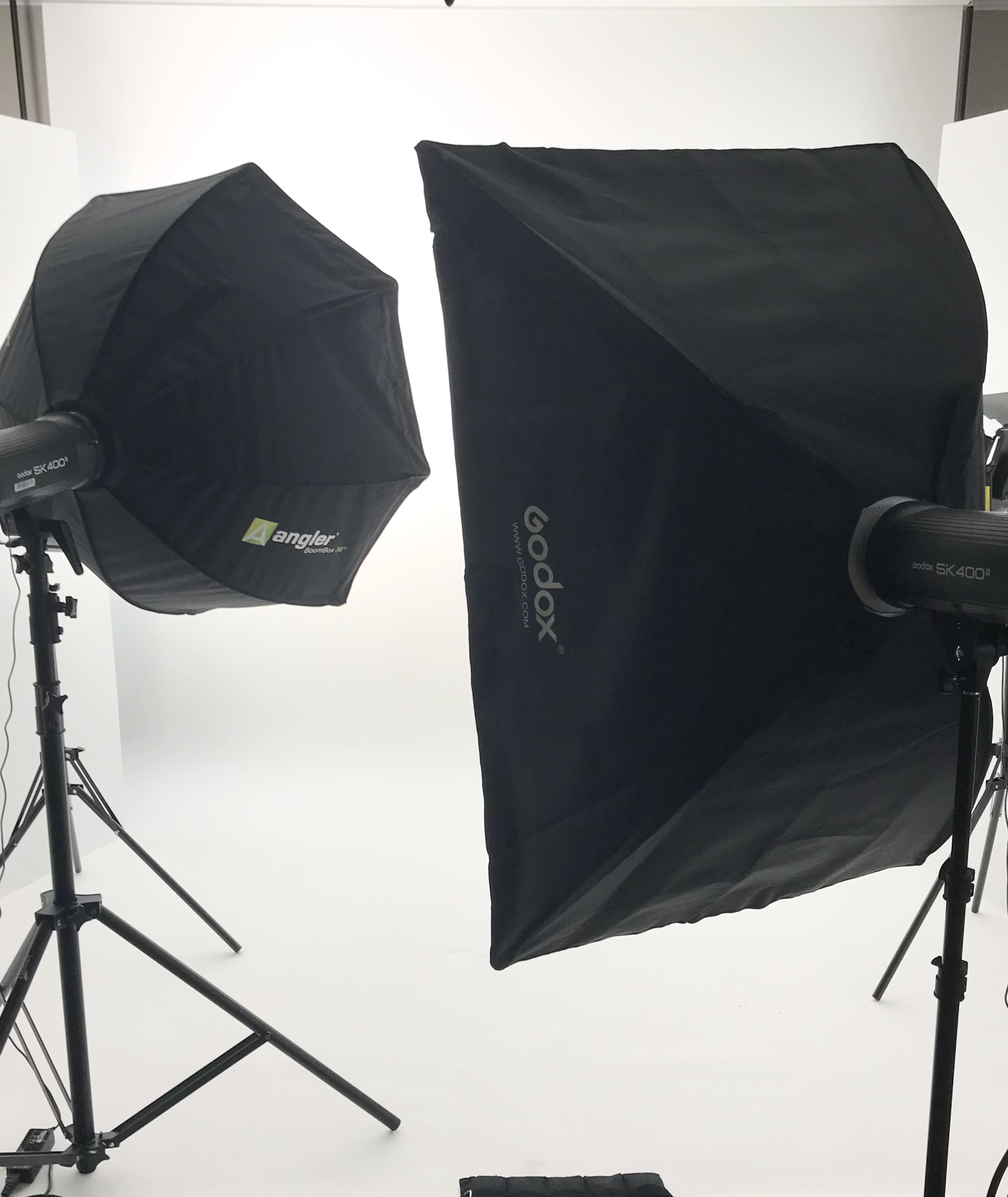 Two softbox light setups on tripods facing a bright, neutral background.