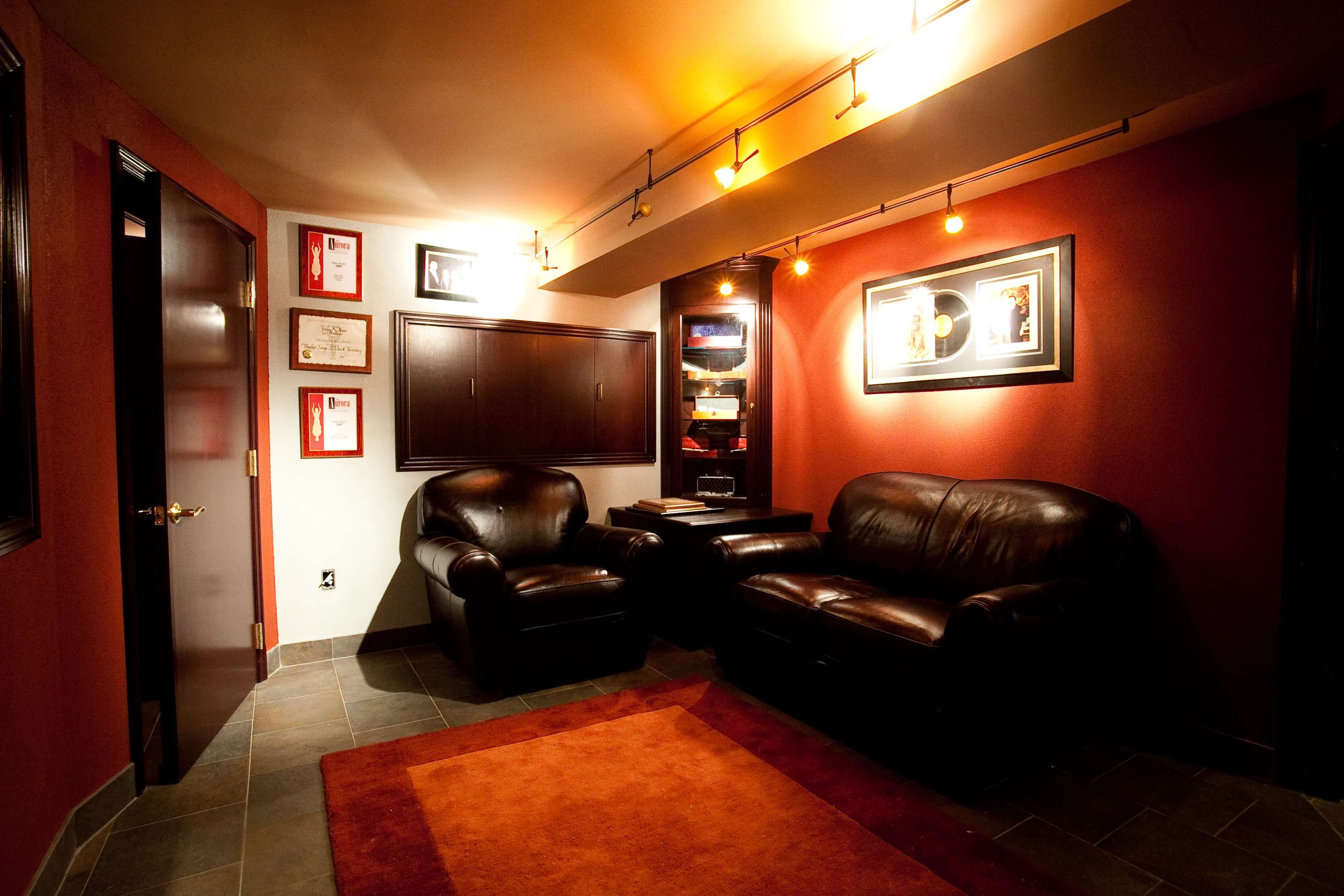 A dimly lit room with two leather chairs, a small coffee table, and framed certificates on the walls.