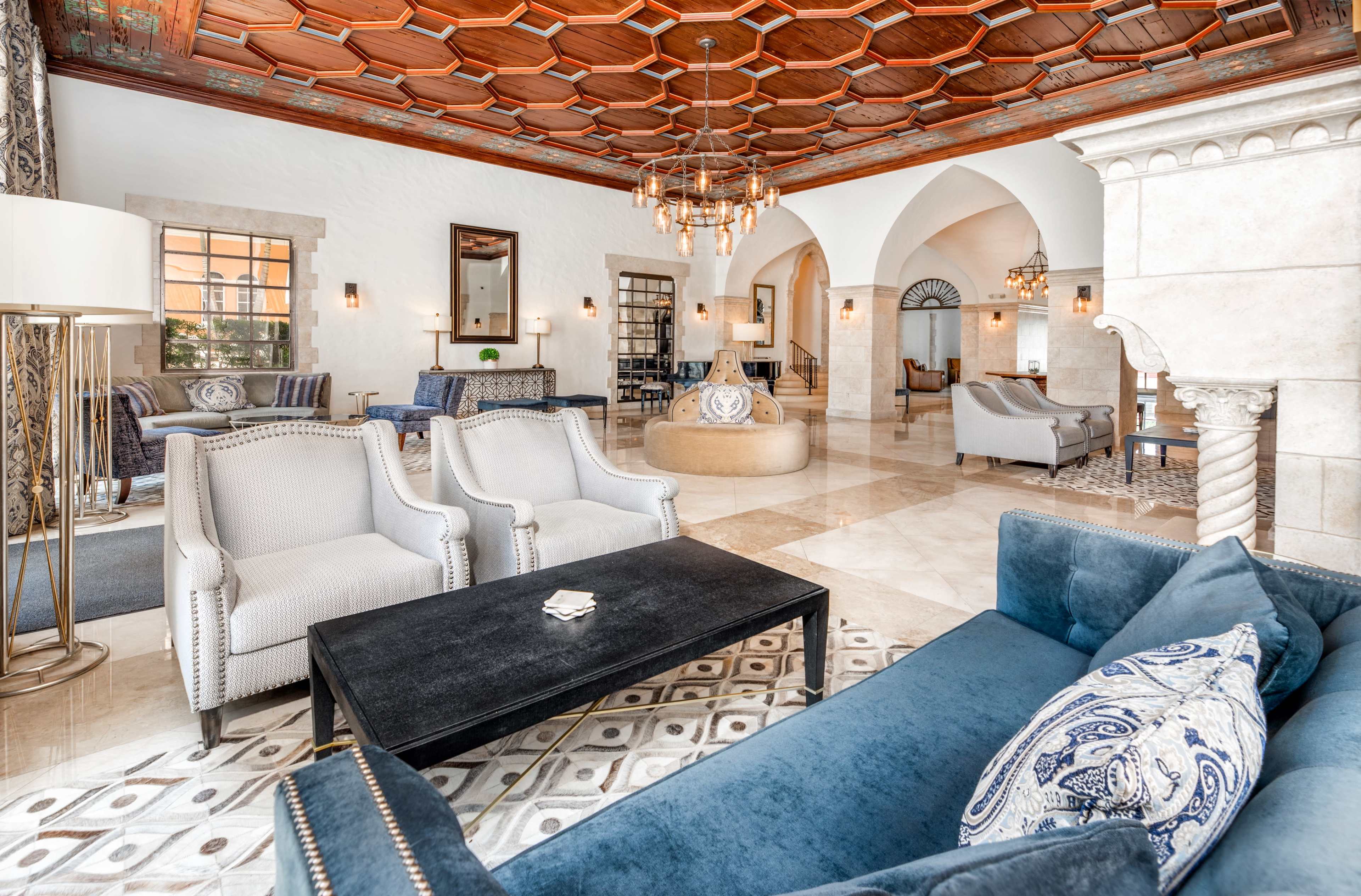 A luxurious lounge area featuring a high wooden ceiling, elegant seating arrangements, and decorative furnishings.