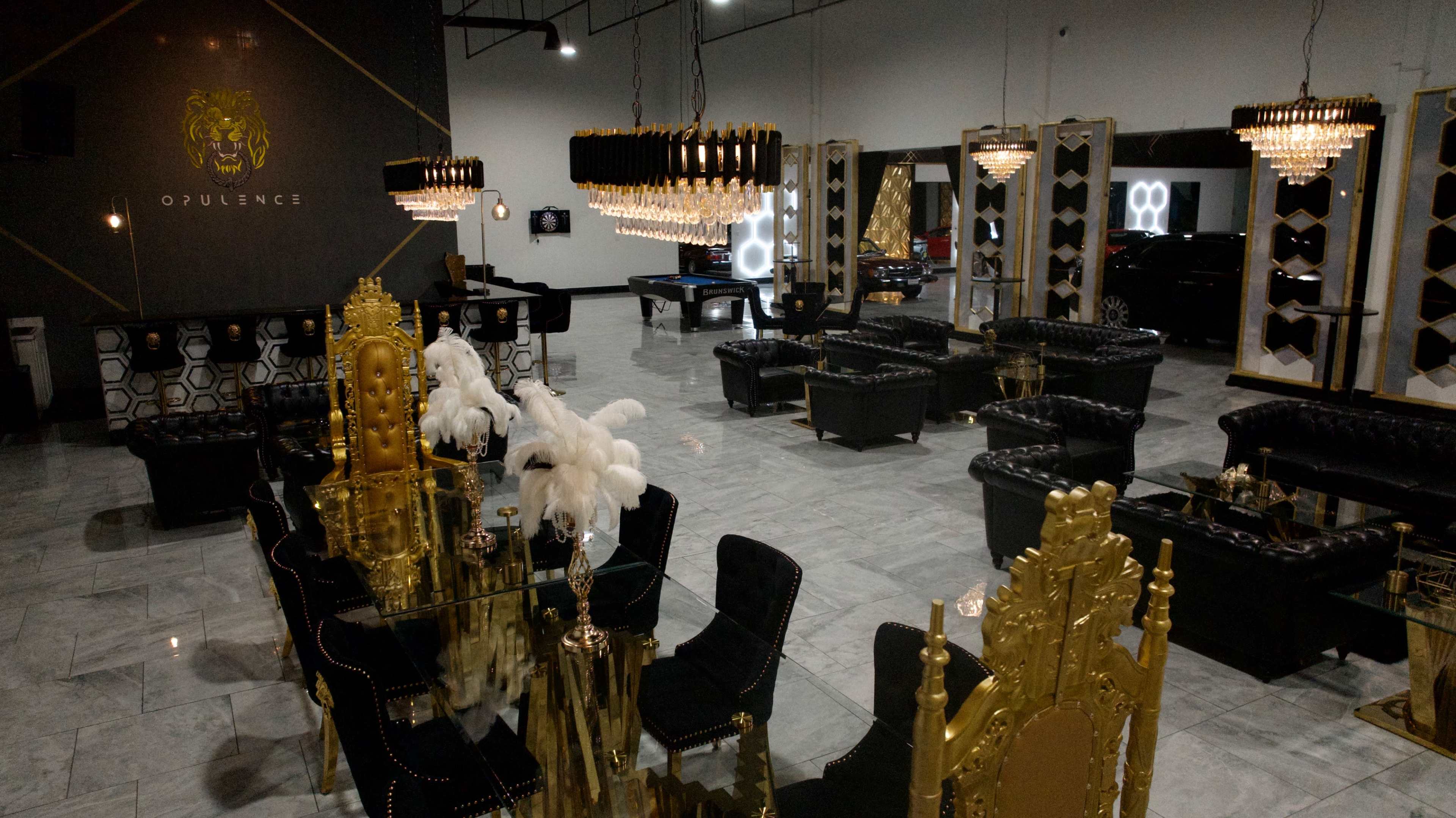 The image shows a luxurious lounge area with black leather seating, golden furnishings, and chandeliers, along with a billiards table in the background.