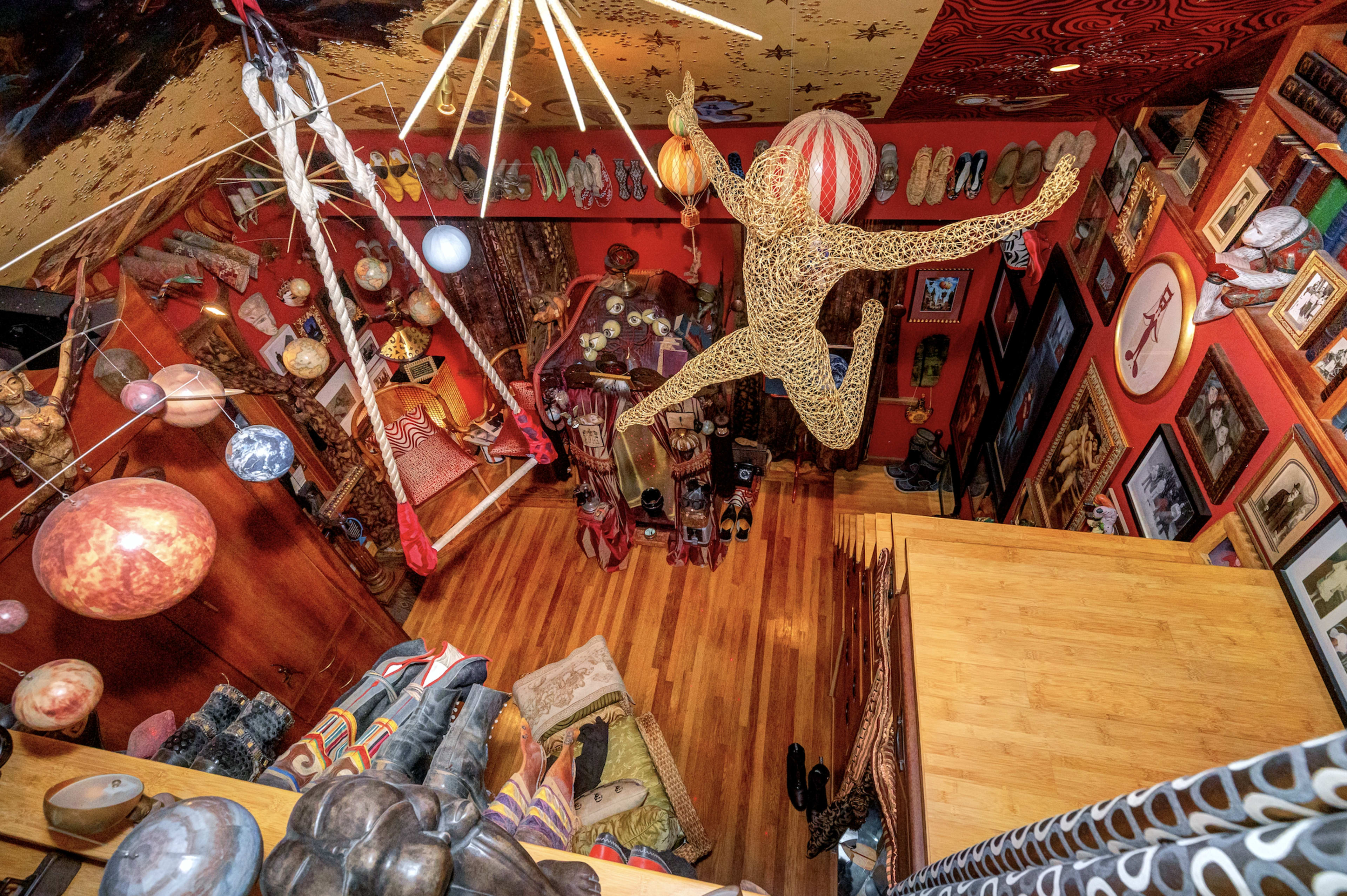 An overhead view of a vibrant room filled with various decorations, including hanging sculptures, patterned walls, and eclectic artwork.