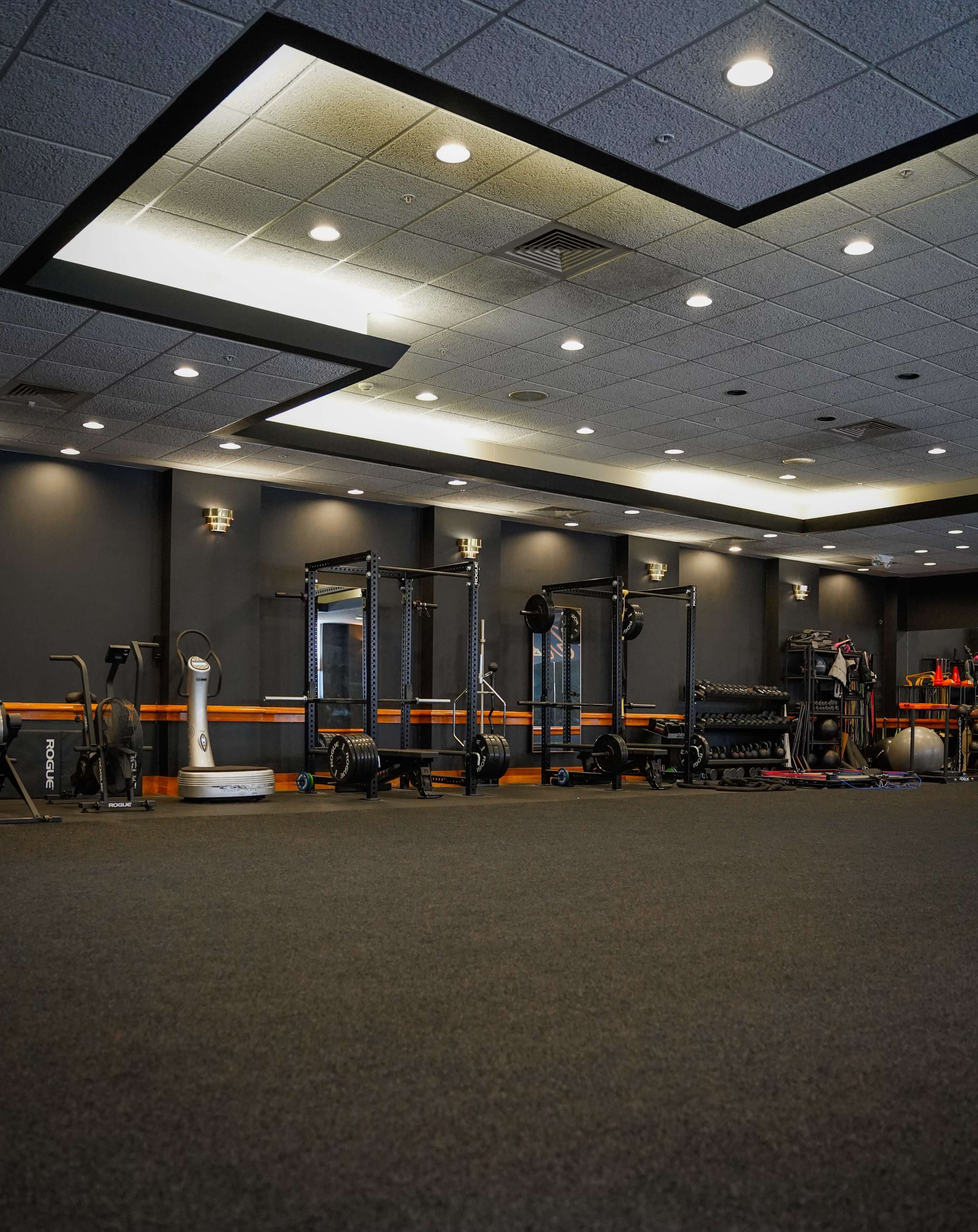 A gym area featuring various exercise equipment including weight racks, cardio machines, and open floor space.