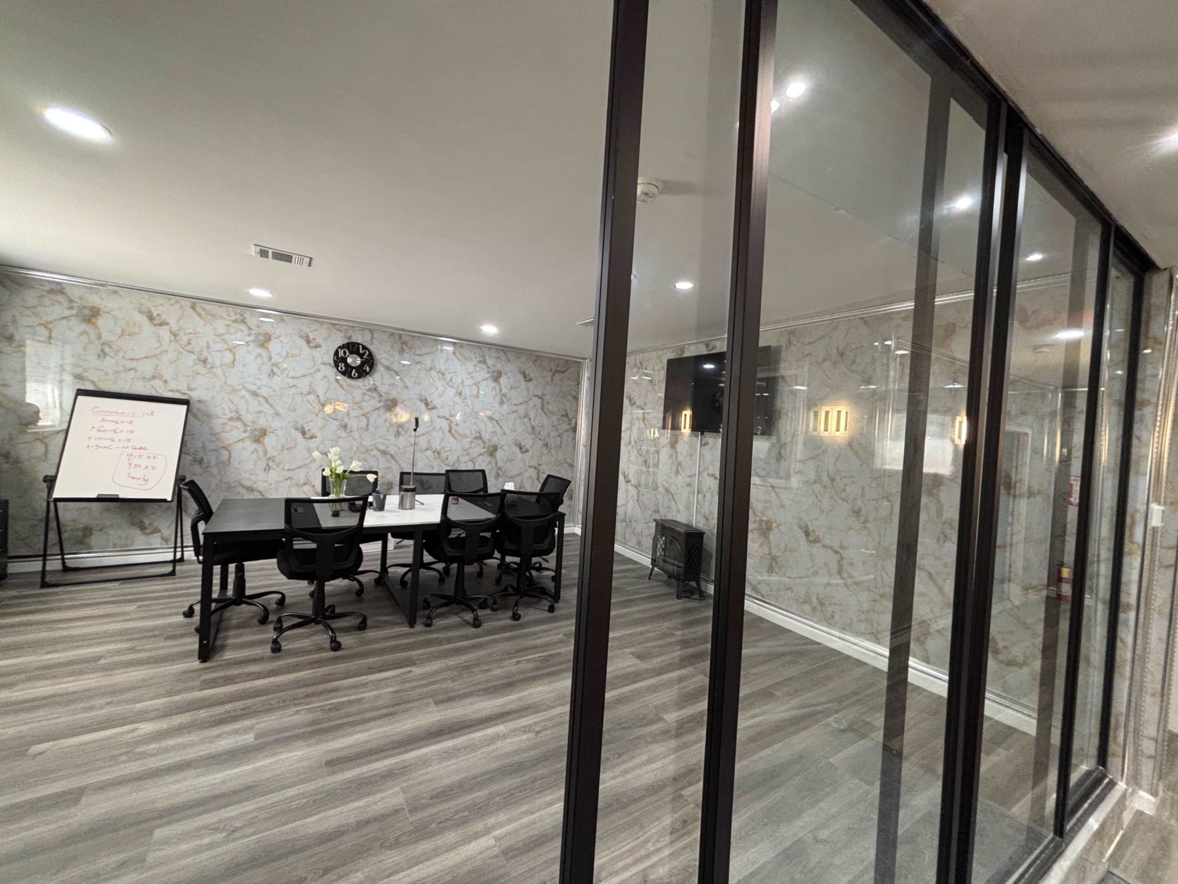 The image shows a modern conference room with a large table and black chairs, surrounded by glass walls and featuring marble-patterned wallpaper.