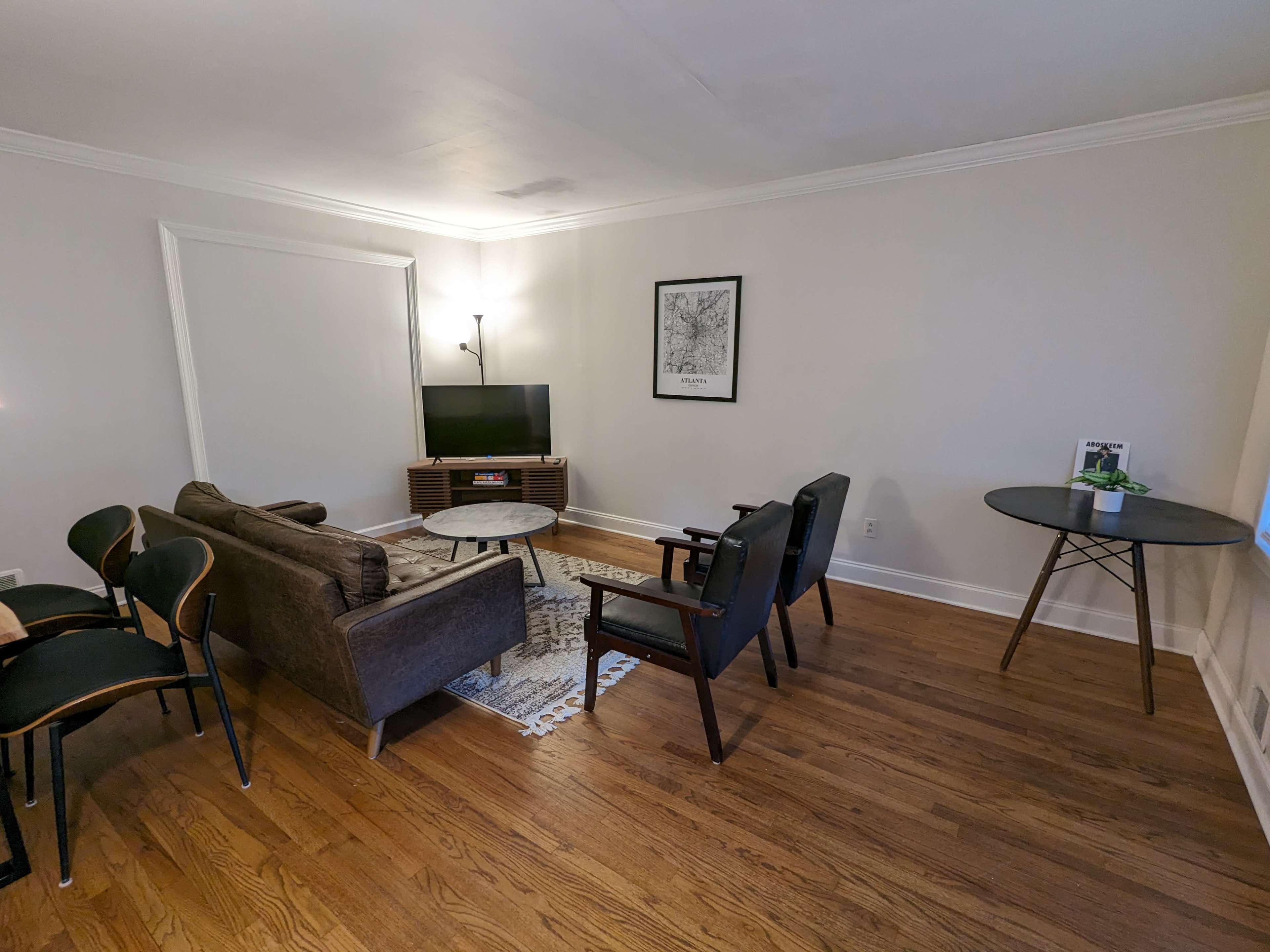 The living room features a sofa, two armchairs, a coffee table, and a television against a light-colored wall.