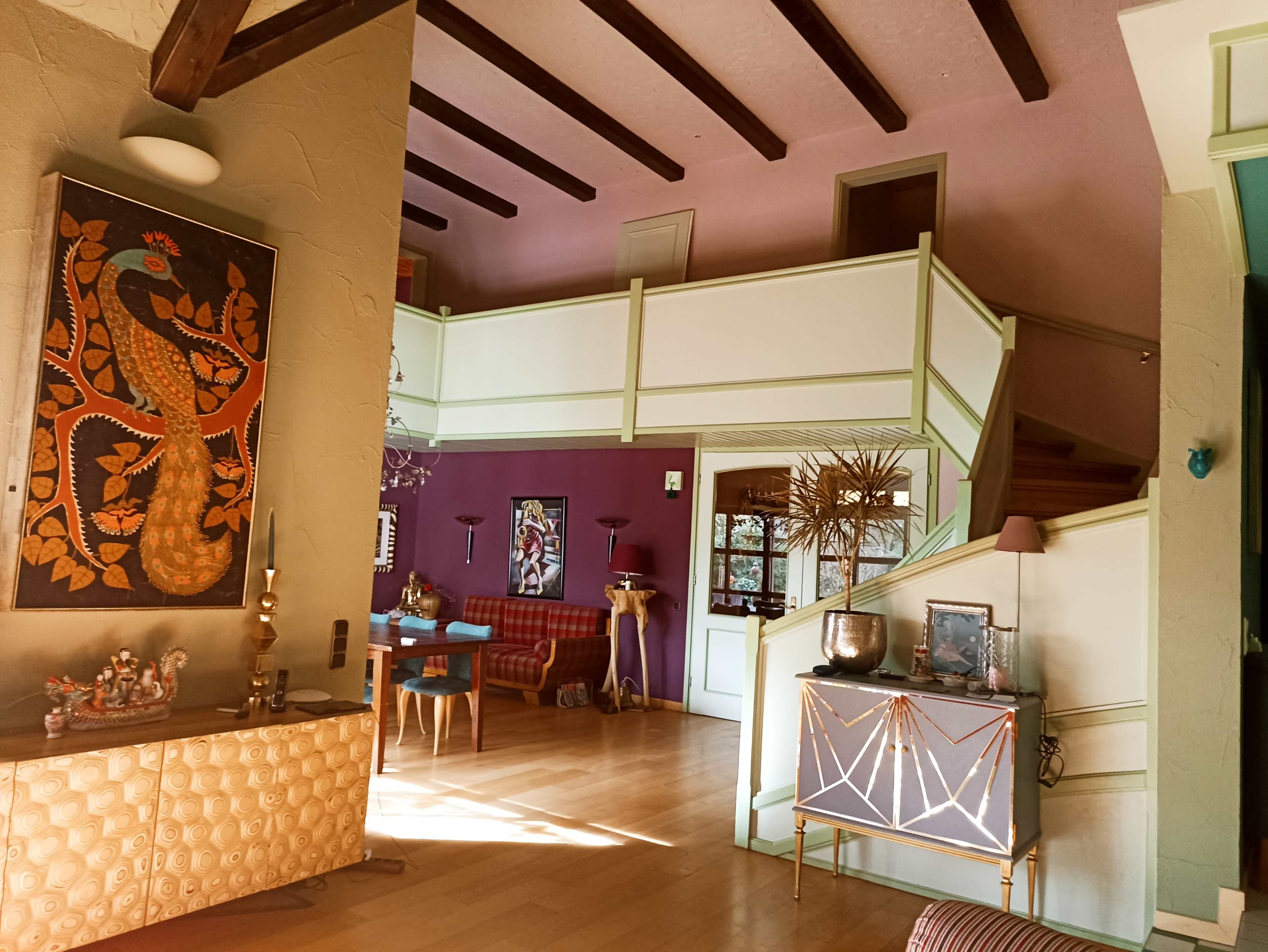 The image shows the interior of a multi-level living space featuring a staircase, a sitting area with a red bench, and colorful wall designs.
