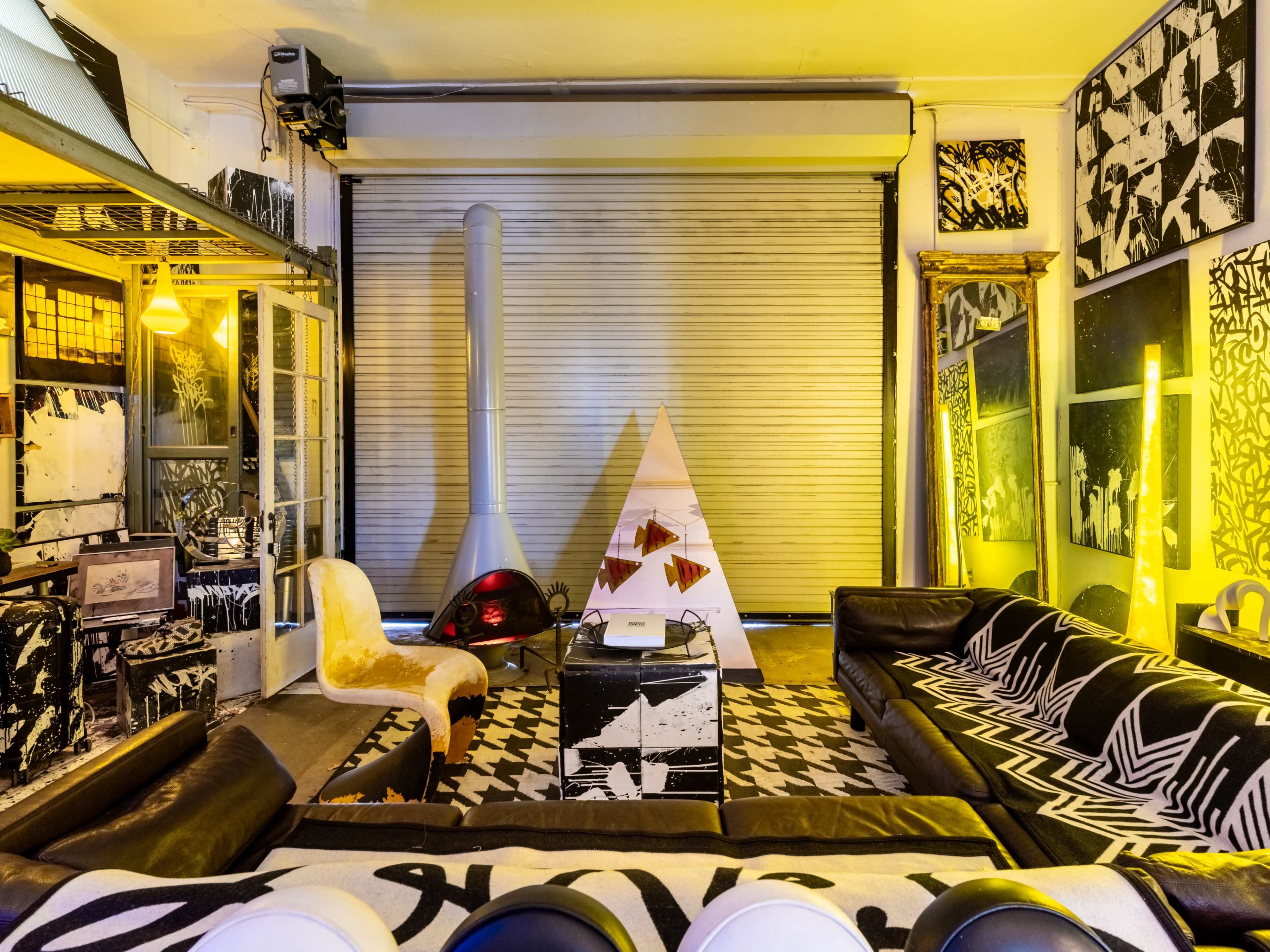 The scene features a modern interior with black and white decor, including a geometric art installation, a cozy seating area with sofas, and an abstract design rug.
