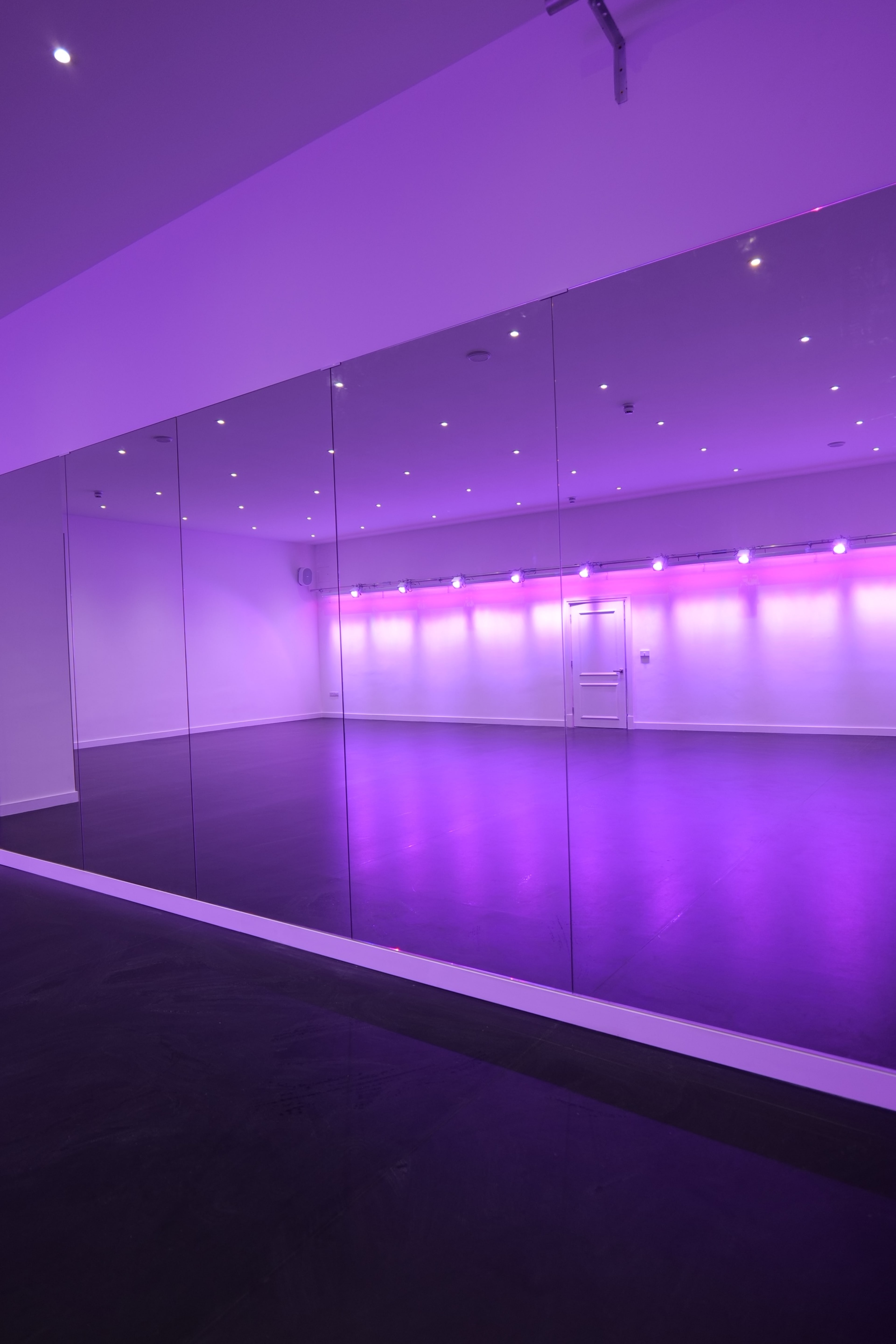 A spacious room with mirrored walls and purple ambient lighting.