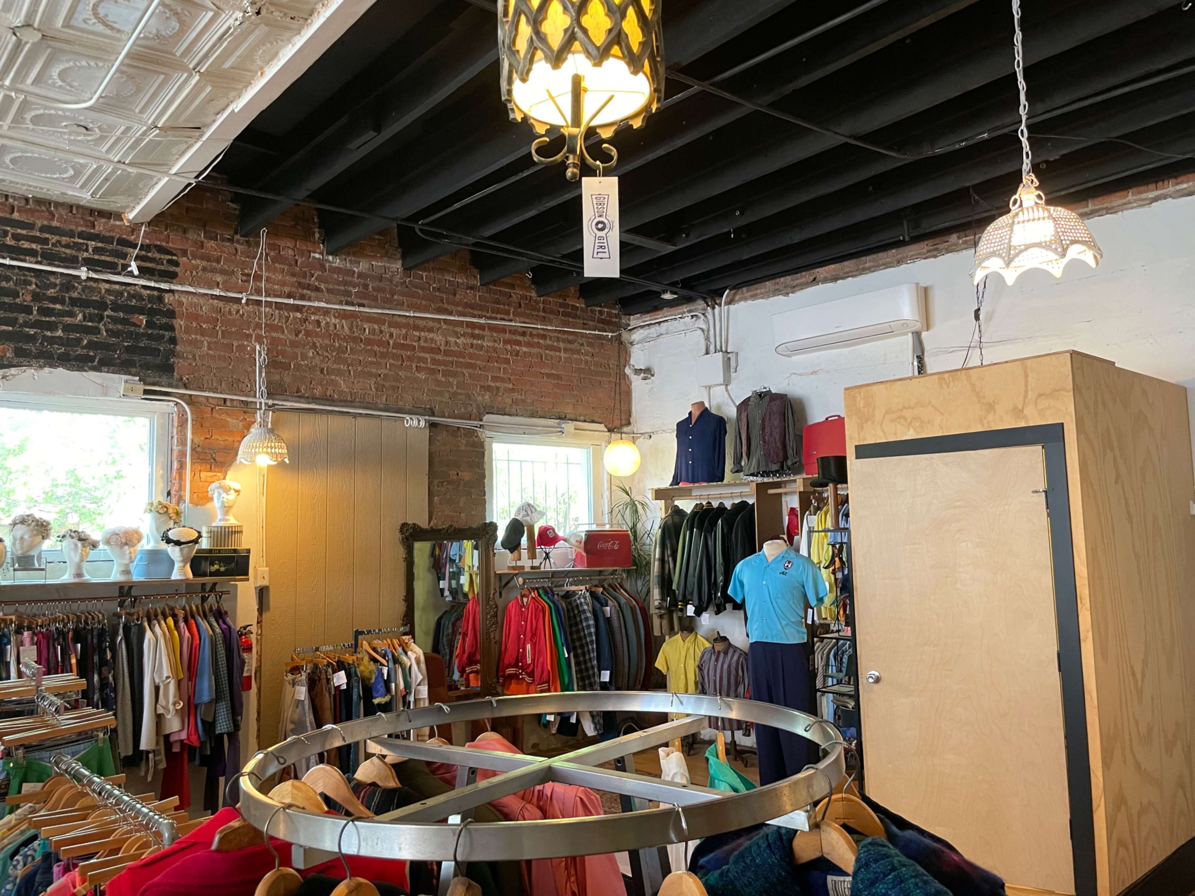 A retail store interior with clothing racks, a circular display fixture, and exposed brick walls.