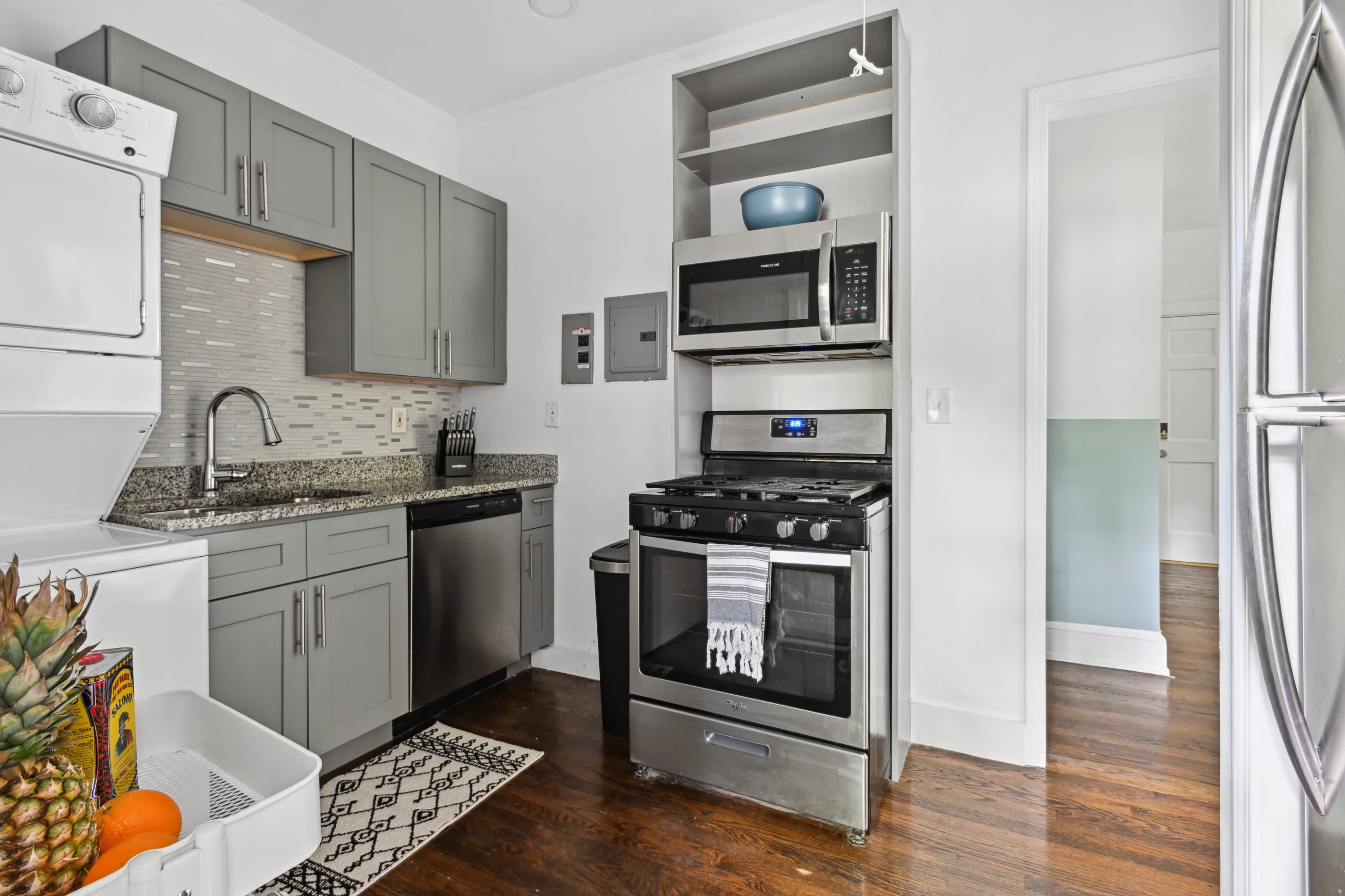 The kitchen features gray cabinetry, stainless steel appliances, and a countertop with a textured backsplash.