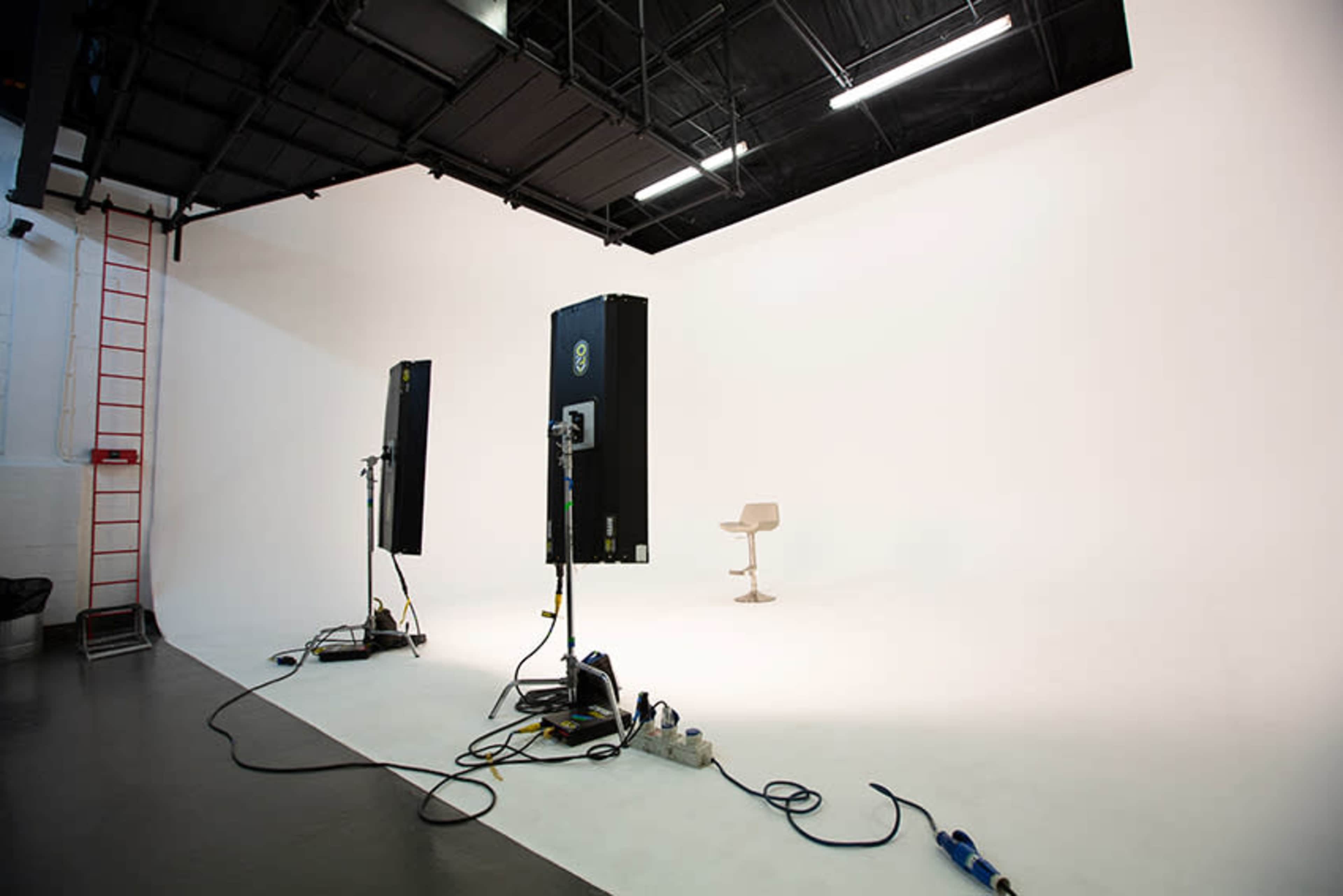 A minimalist photography studio with two large lights positioned on either side of a single chair against a white backdrop.