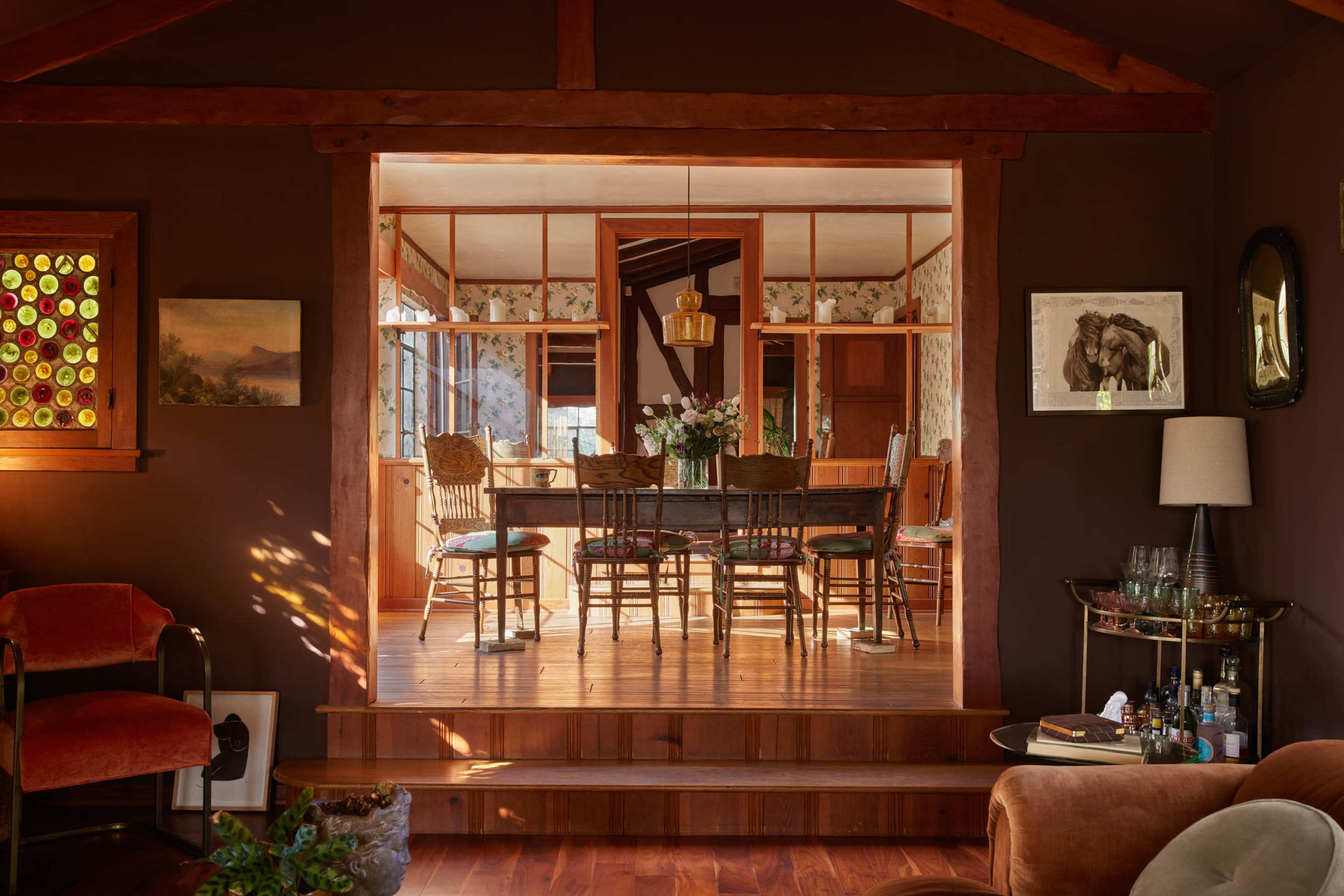 A cozy interior space features a living area with an orange chair and a view of a dining room through an open archway.