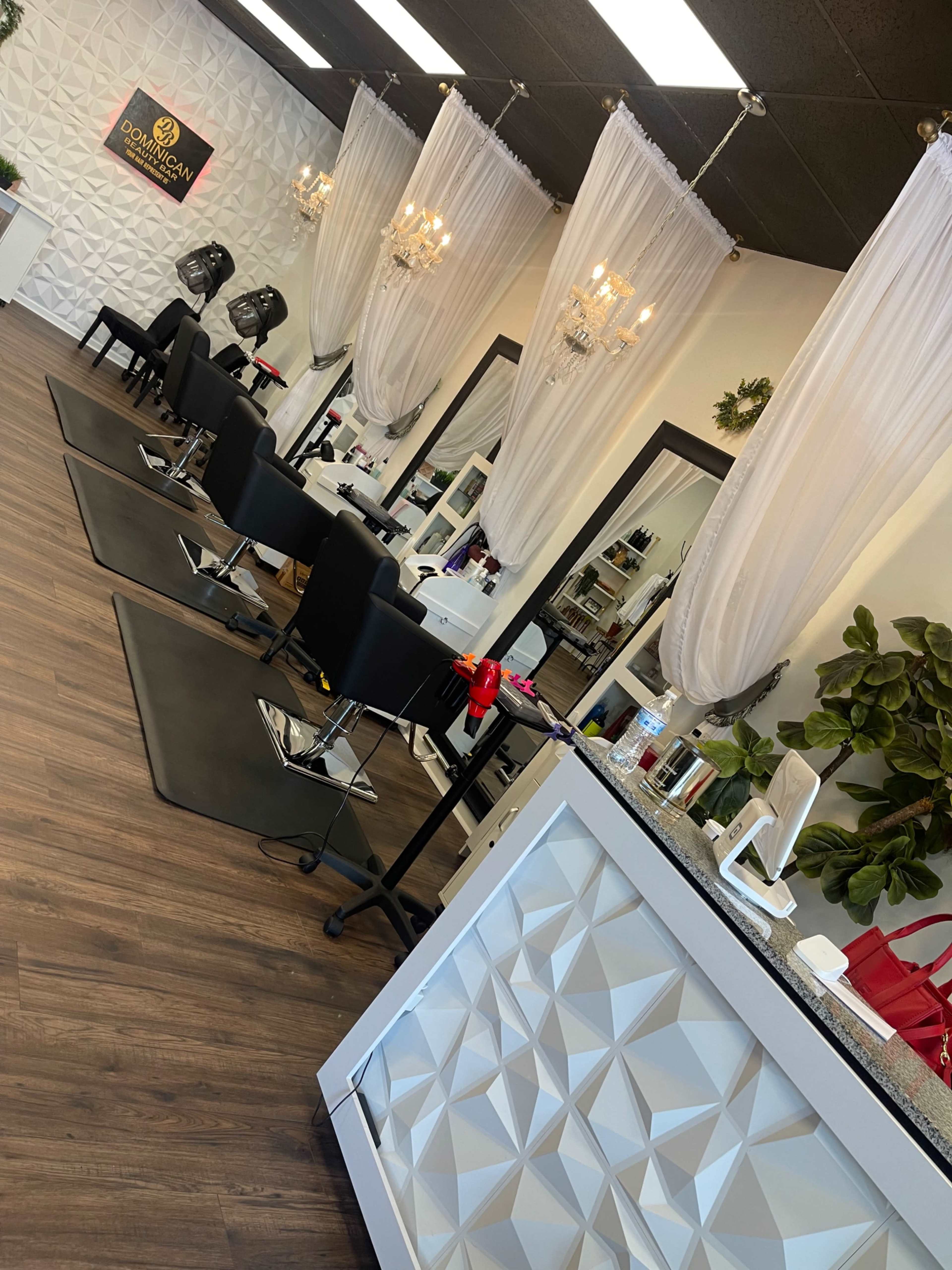The image shows a beauty salon with several styling chairs, mirrors, and elegant chandeliers.