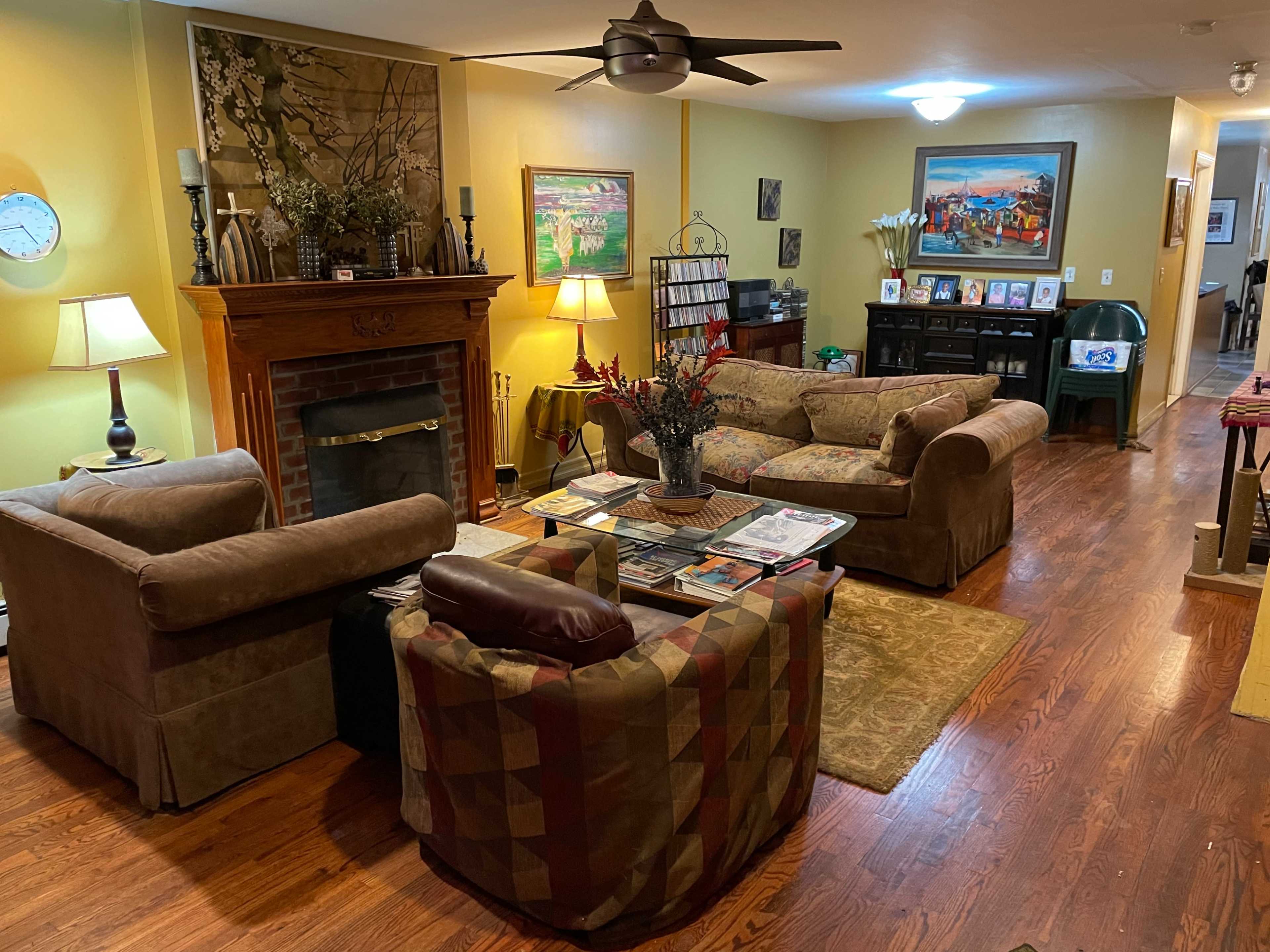 The living room features two couches facing a coffee table, with a fireplace and decorative artwork on the walls.